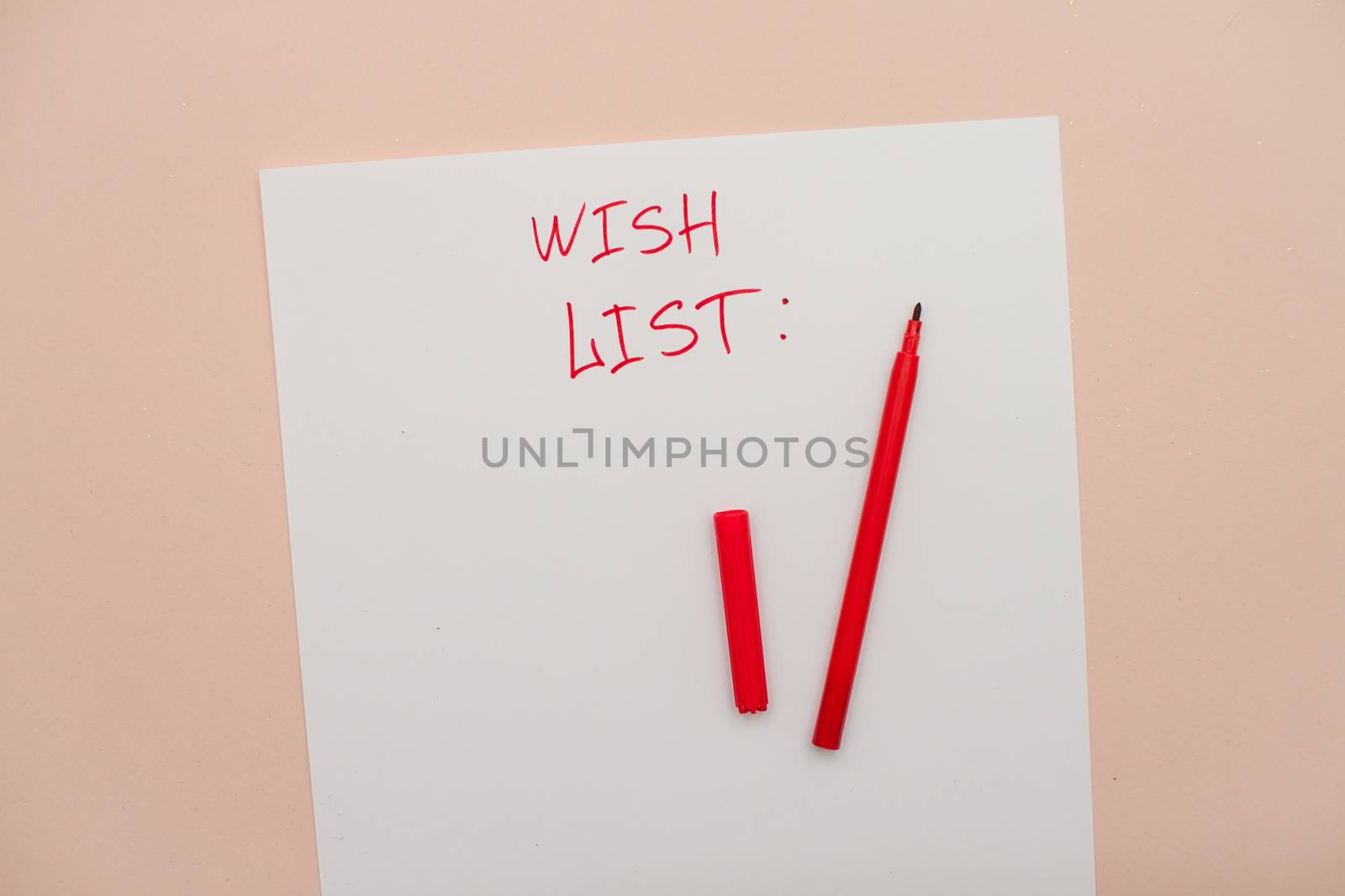 Inscription in red felt-tip pen wish list on a white blank sheet of paper. New Year's wish list. by malyshkamju