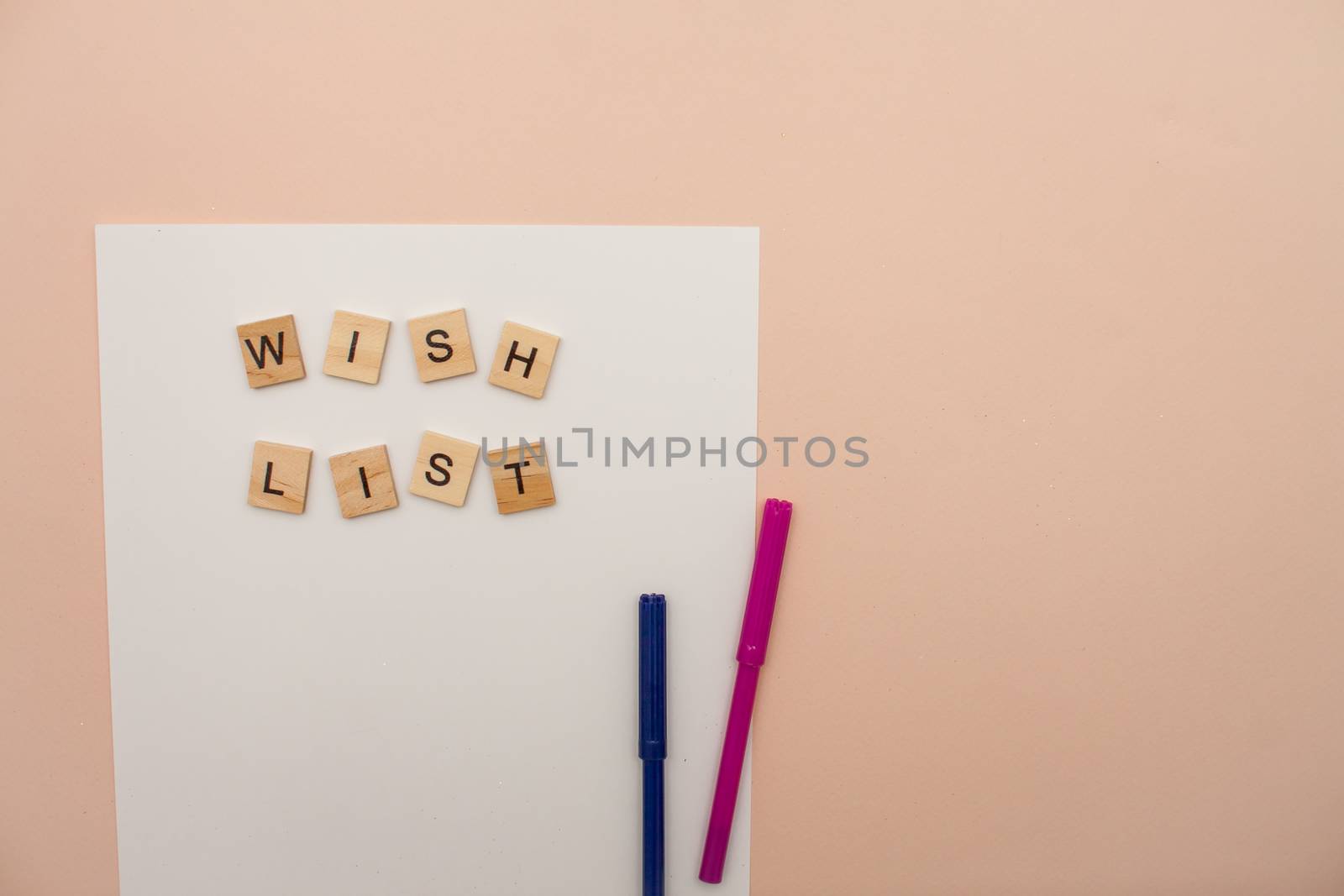 Inscription from wooden blocks wish list on a white blank sheet of paper. New Year's wish list. by malyshkamju