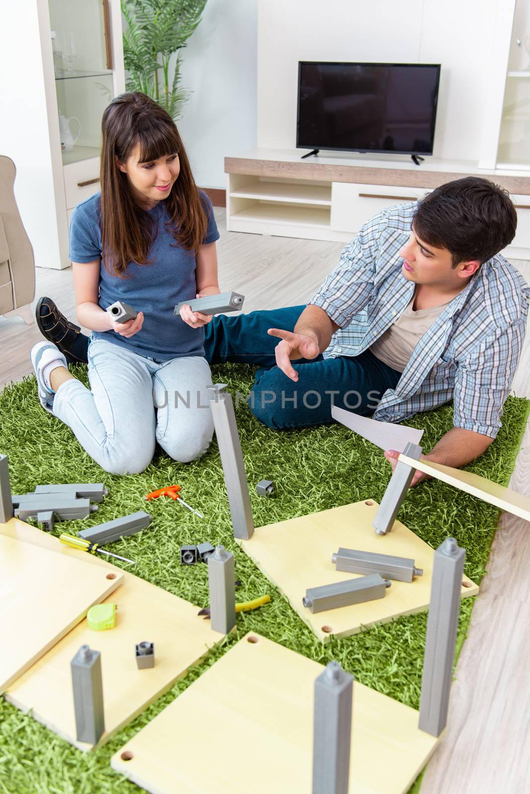 Young family assembling furniture at new house by Elnur