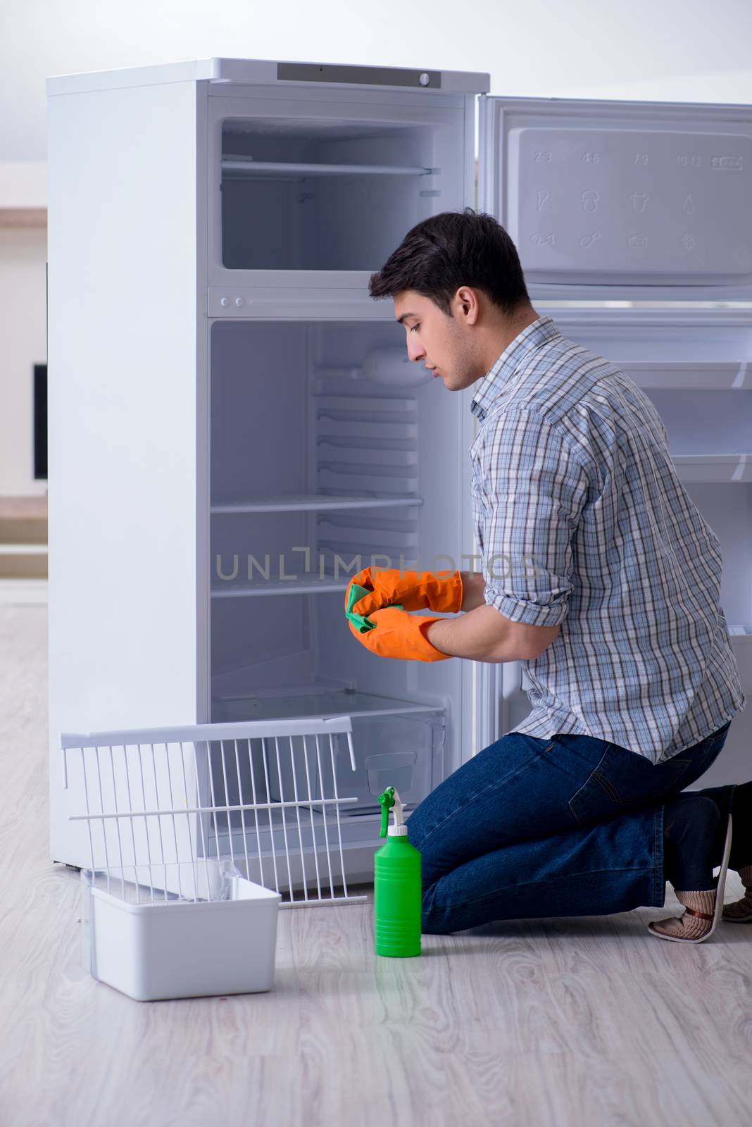 Man cleaning fridge in hygiene concept by Elnur