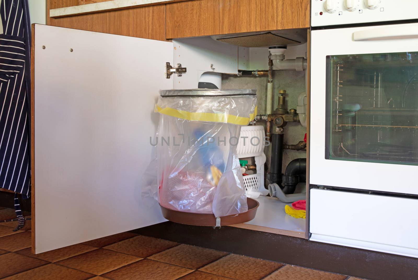 Rubbish bin hanging on kitchen cupboard door by michaklootwijk