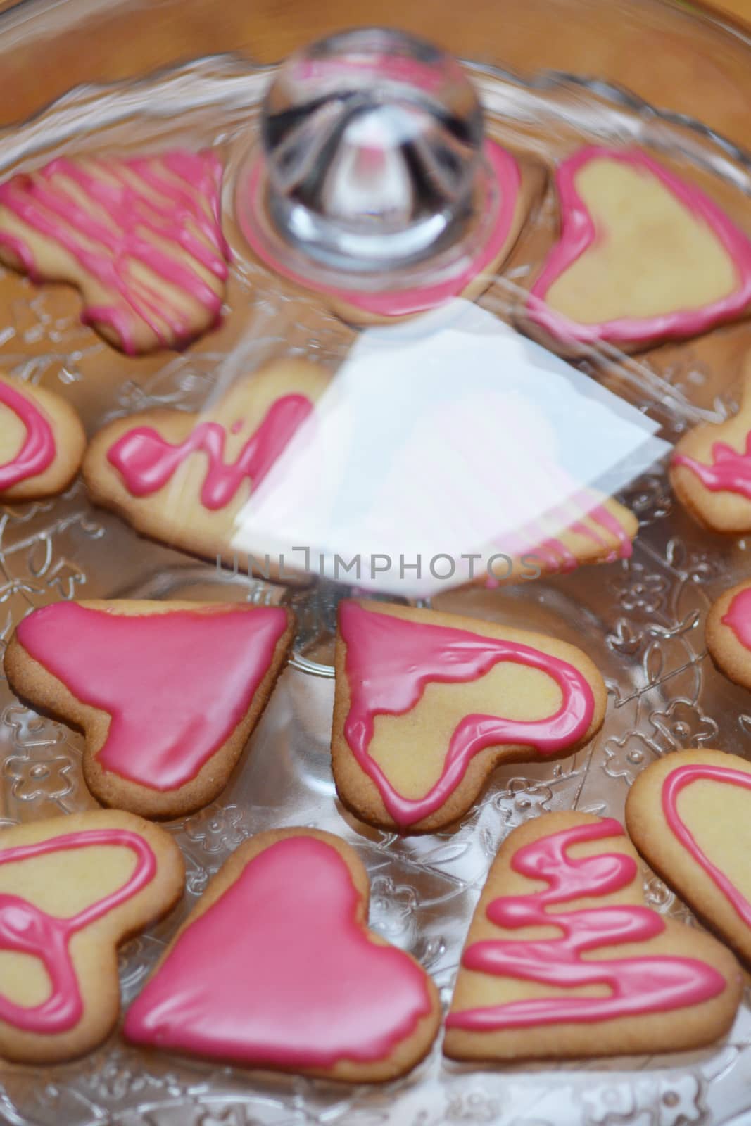 Heart shaped cookies with pink sugar icing under the glass bell