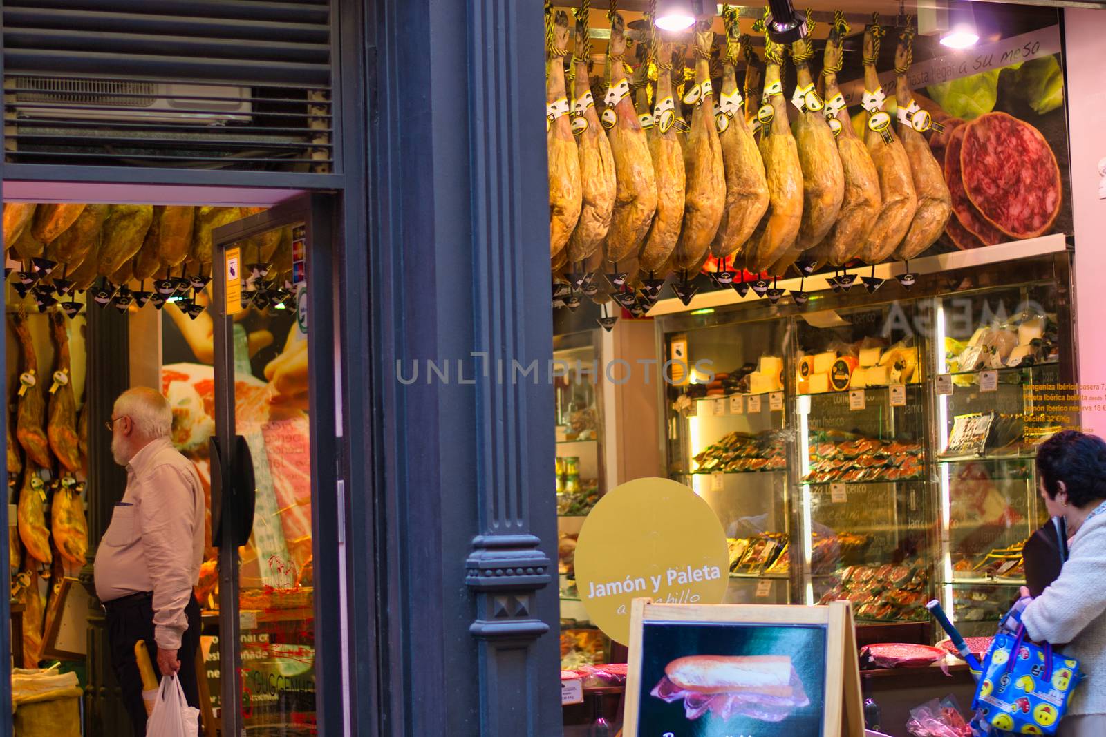 People shopping for typical iberian jamon or ham in Bilbao, Spain. Store exterior and shop window. by kb79