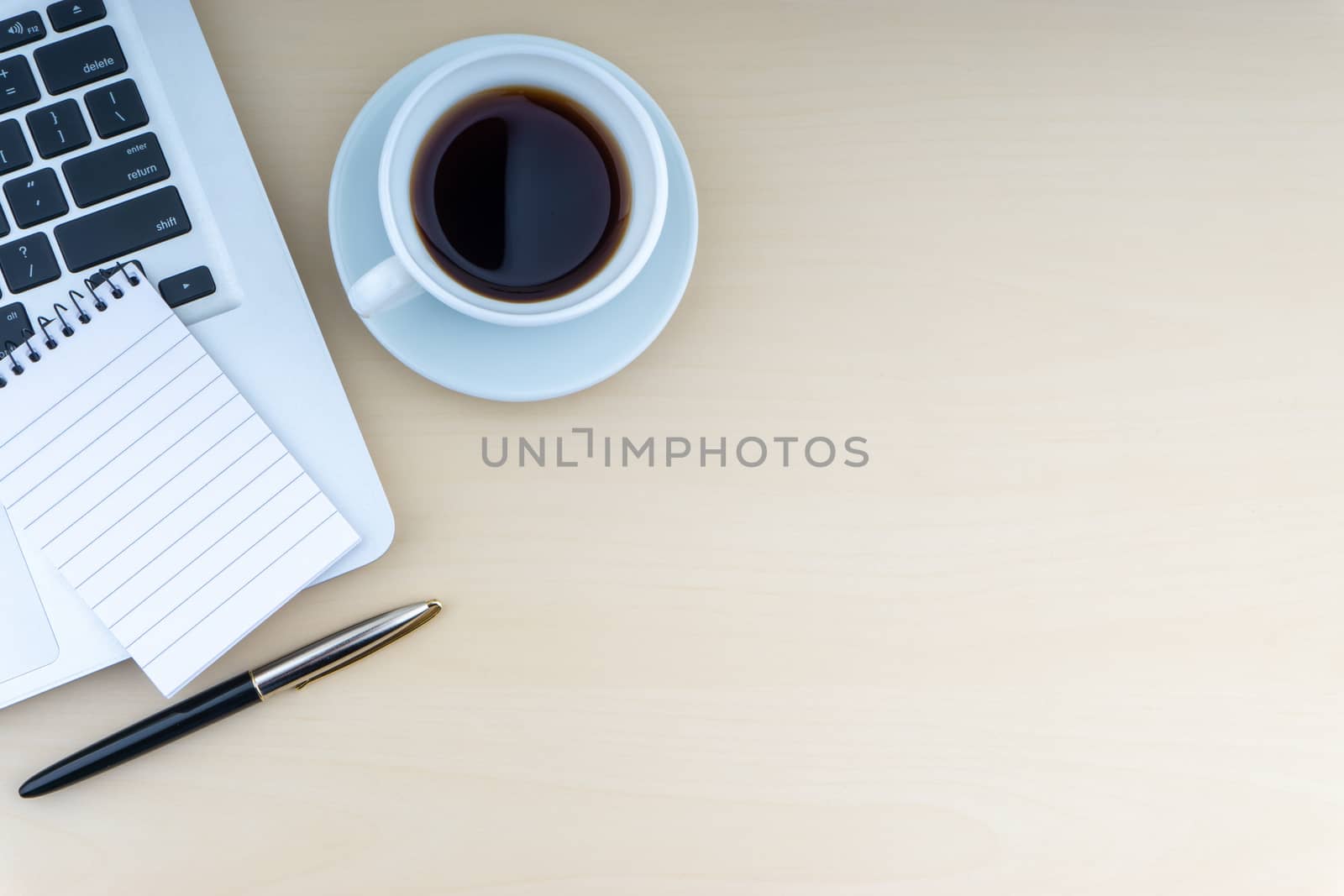 Laptop, notepad, fountain pen and cup of coffee on wooden background. Business and copy space concept.
