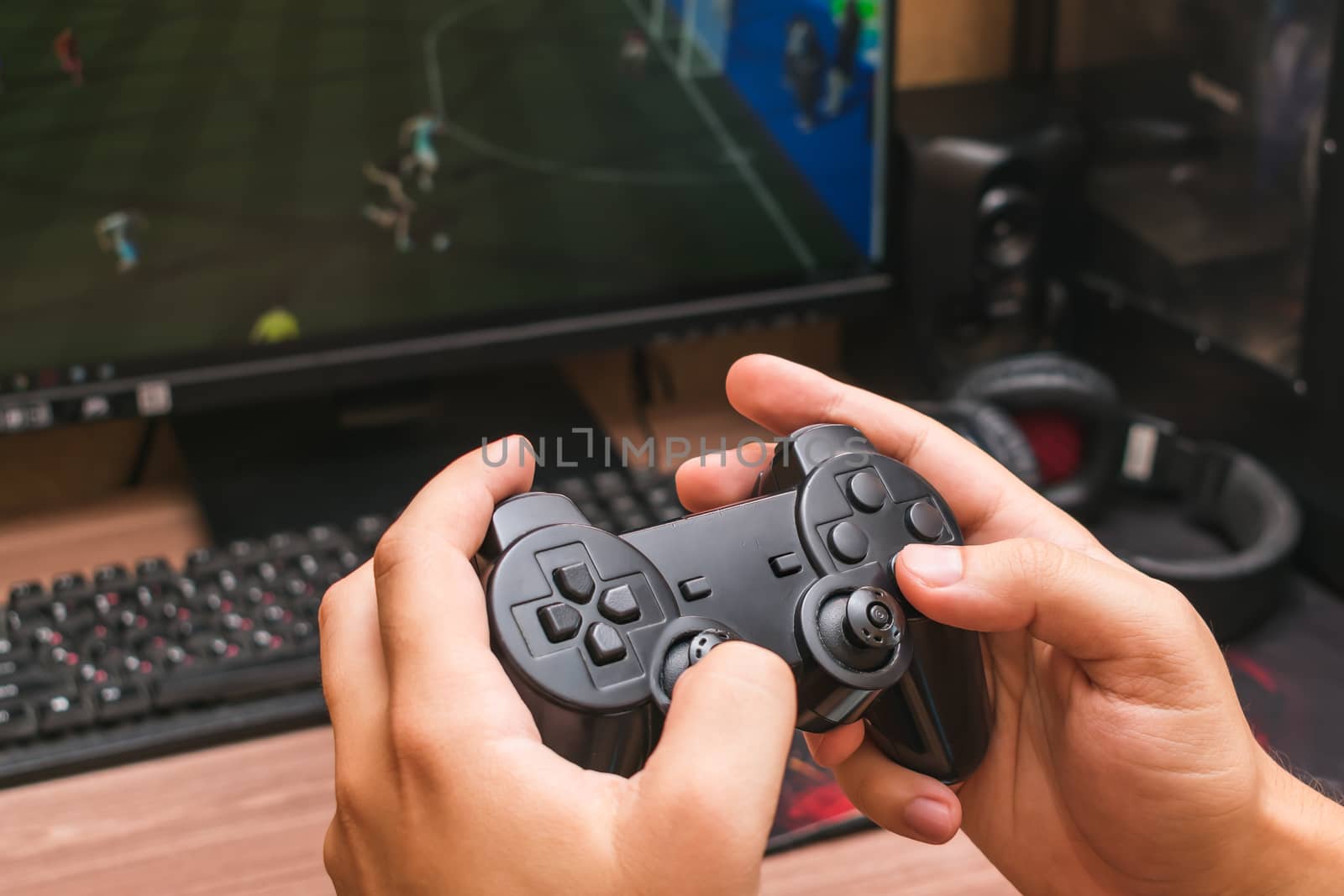 Man holds a game joystick in his hands while playing a video game
