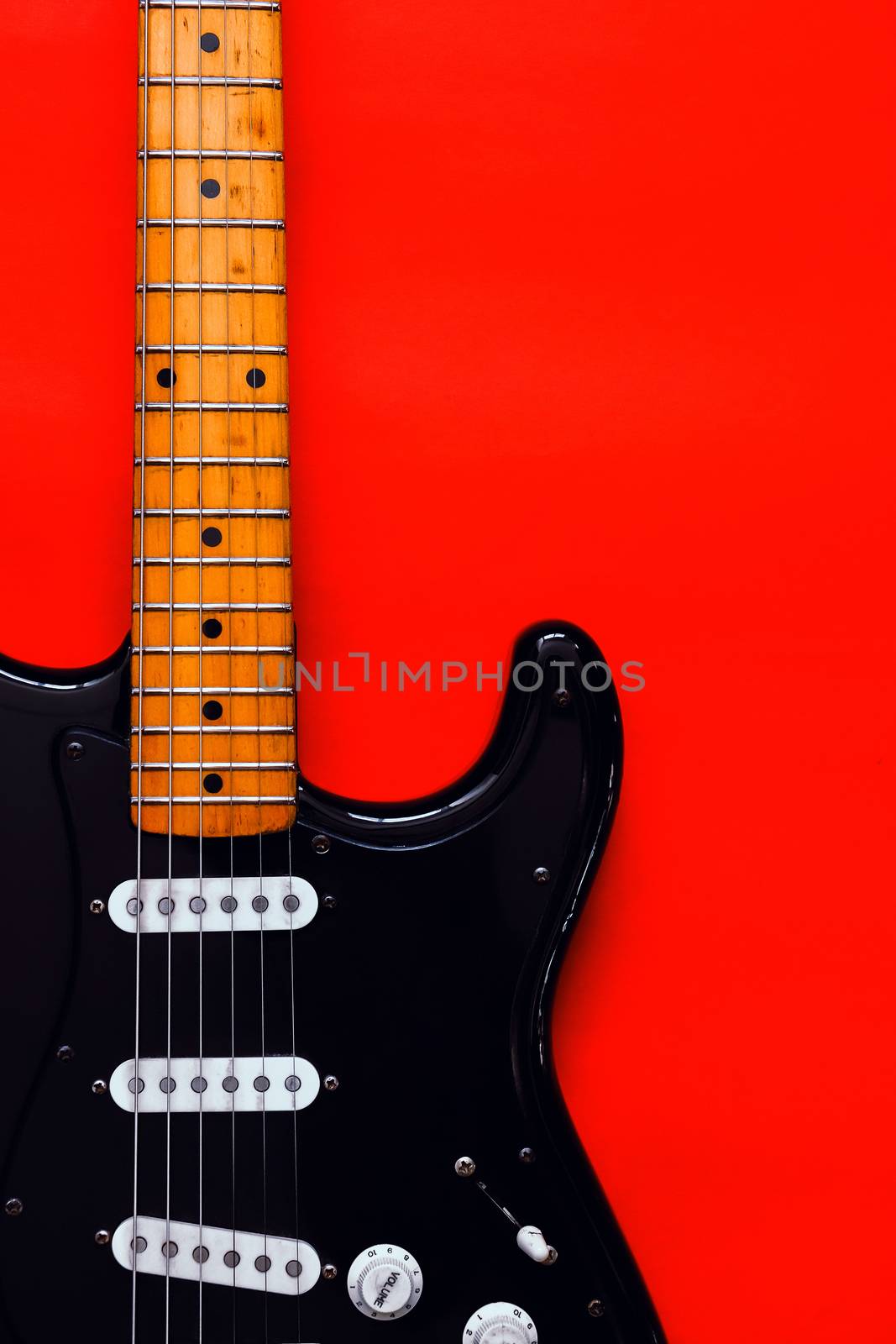 Detail of Electric Guitar on a red background.