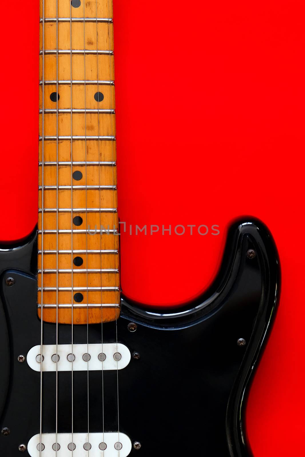 Detail of Electric Guitar on a red background.