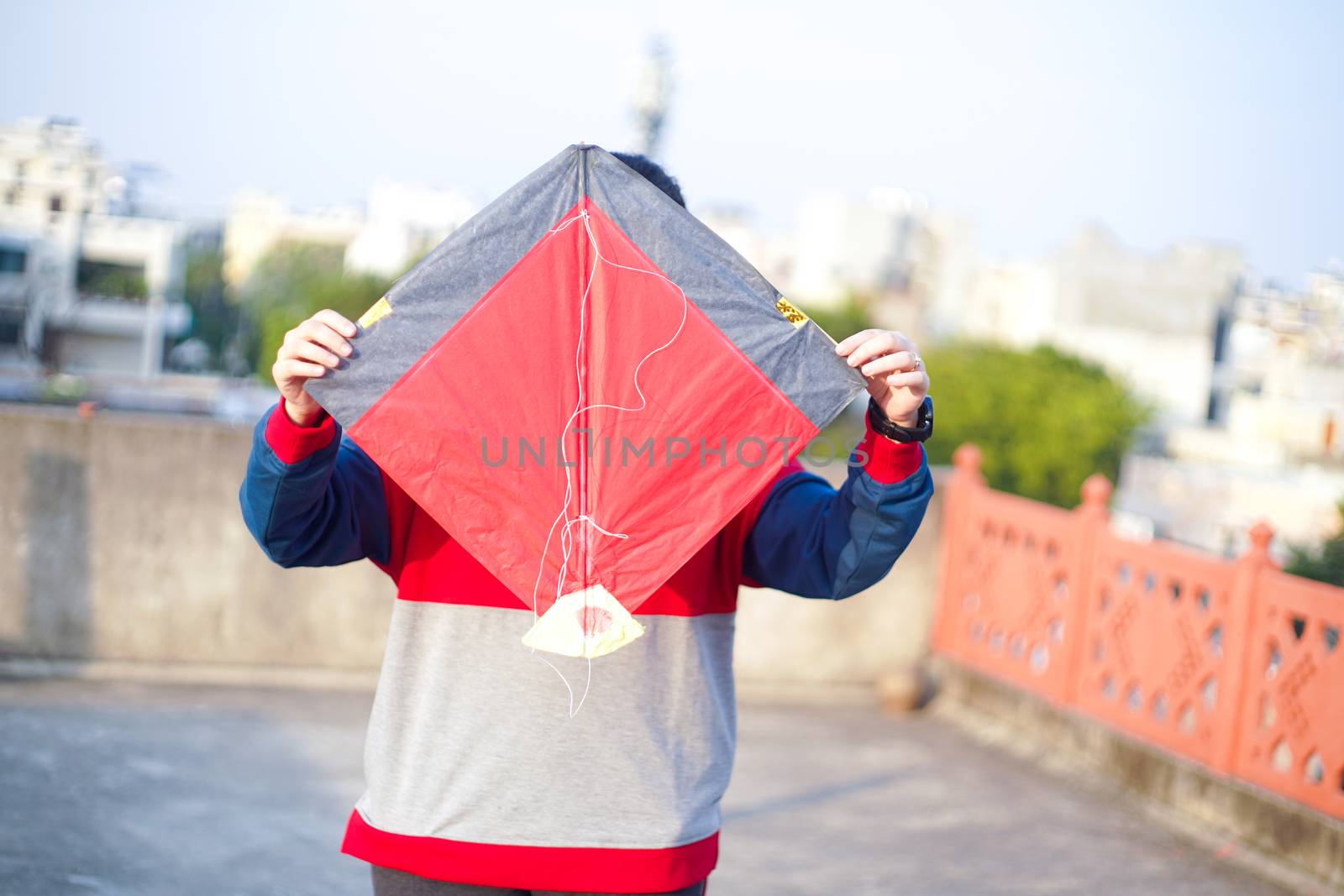 Lady holding a indian fighting kite aloft in order to launch it on the indian harvest festival of makar sankranti or uttarayana in Rajasthan Gujarat by Shalinimathur