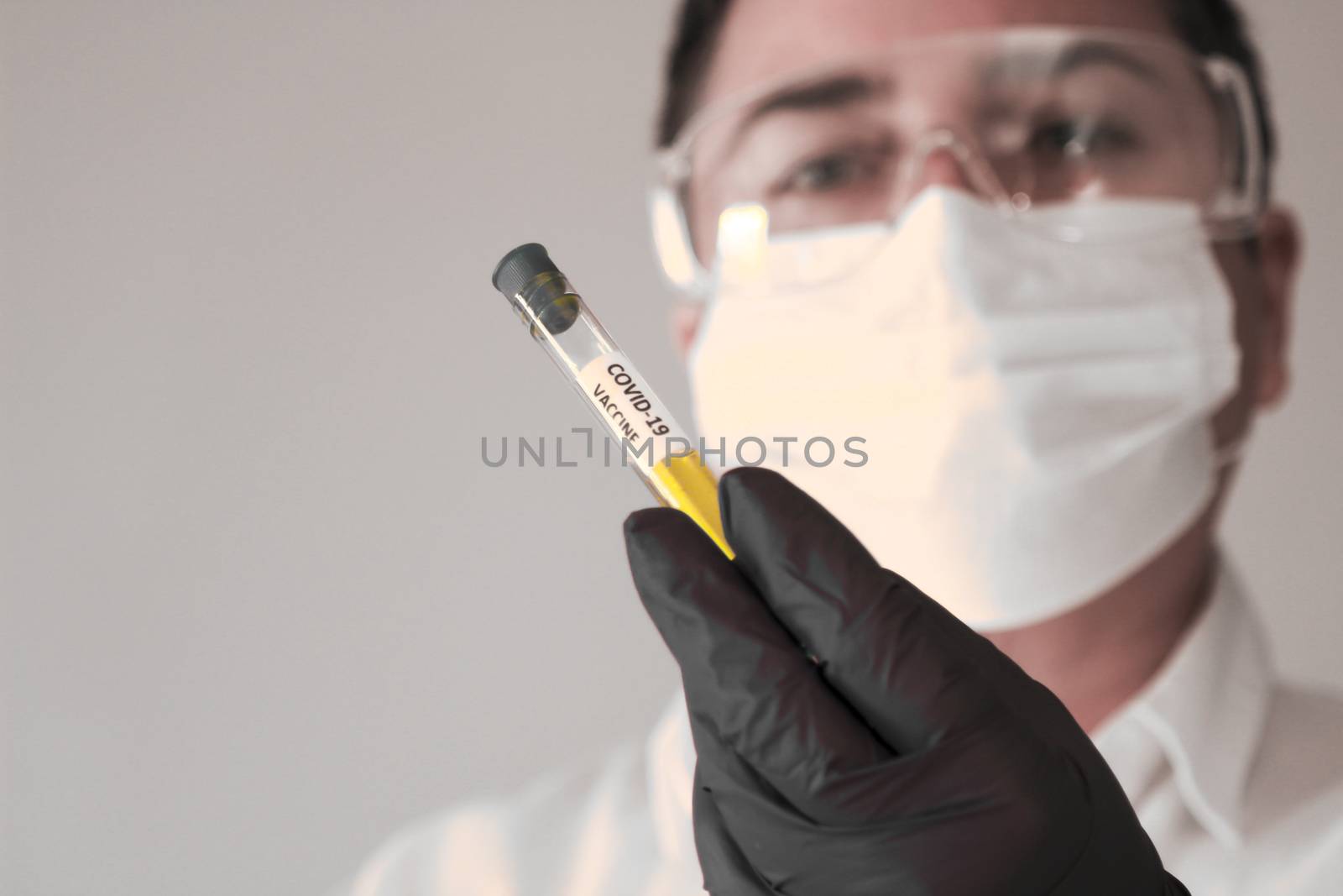 Madrid, Spain- November 25, 2020: Laboratory assistant wearing protective glasses and surgery gloves holding test tube of Covid-19 virus vacine
