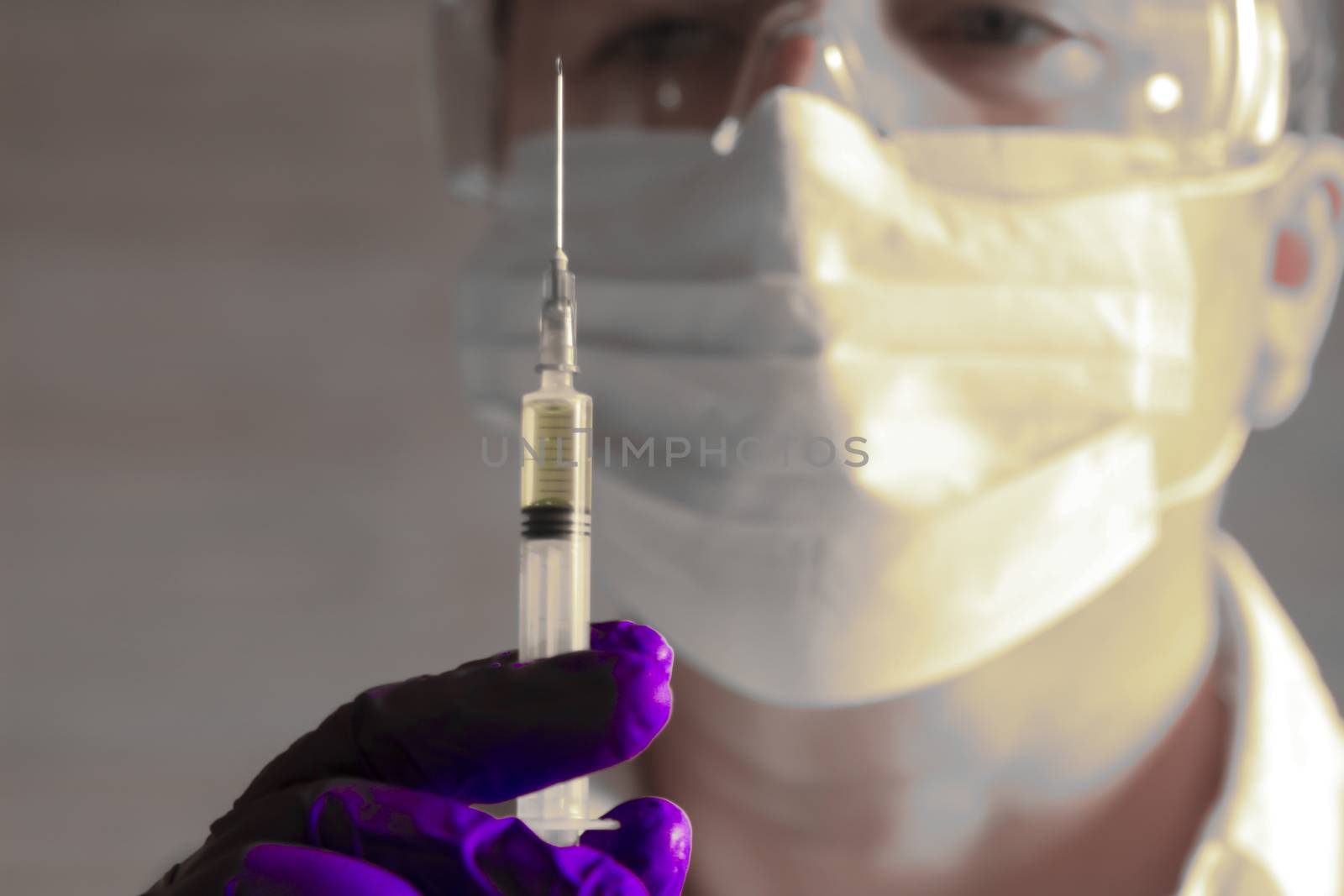 Laboratory assistant wearing protective glasses and surgery gloves holding a syringe with Covid-19 virus vaccine