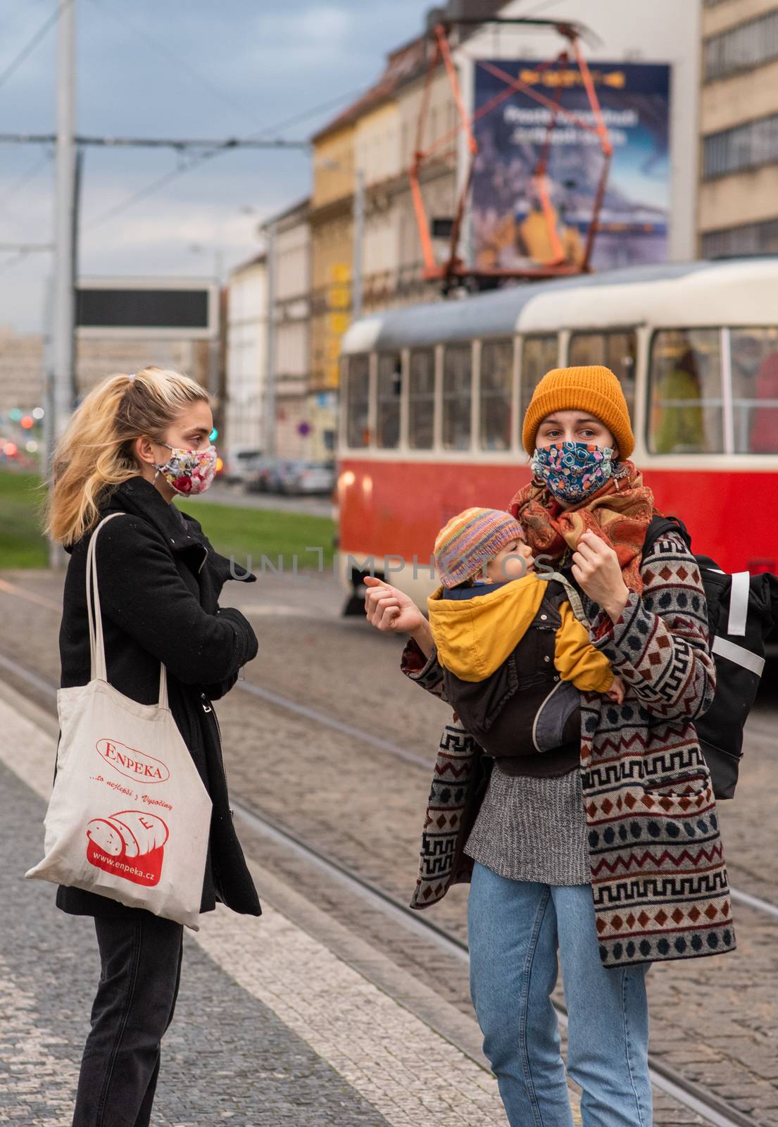 11-23-2020. Prague, Czech Republic. People walking and talking outside during coronavirus (COVID-19) at Hradcanska metro stop in Prague 6. Mother and child waiting tram.