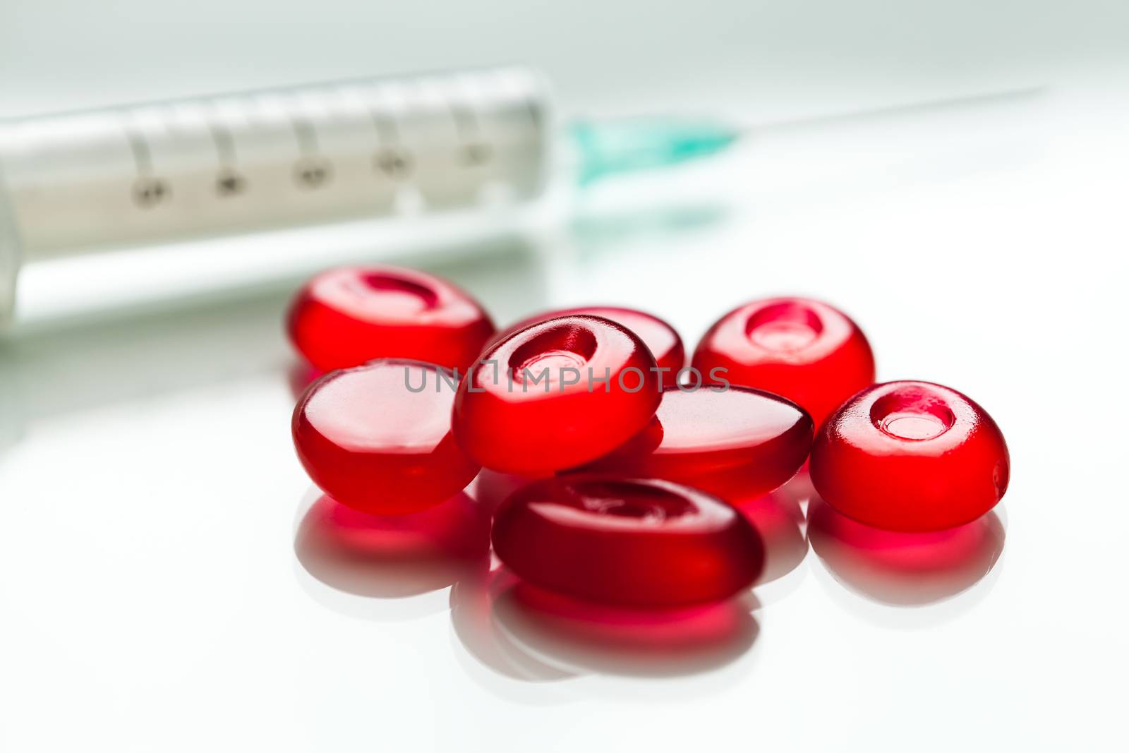 Bunch of red pills & syringe with needle,isolated on white surface with reflection,cure & medication for Coronavirus COVID-19 virus disease,hope & faith in research for vaccine,concept illustration