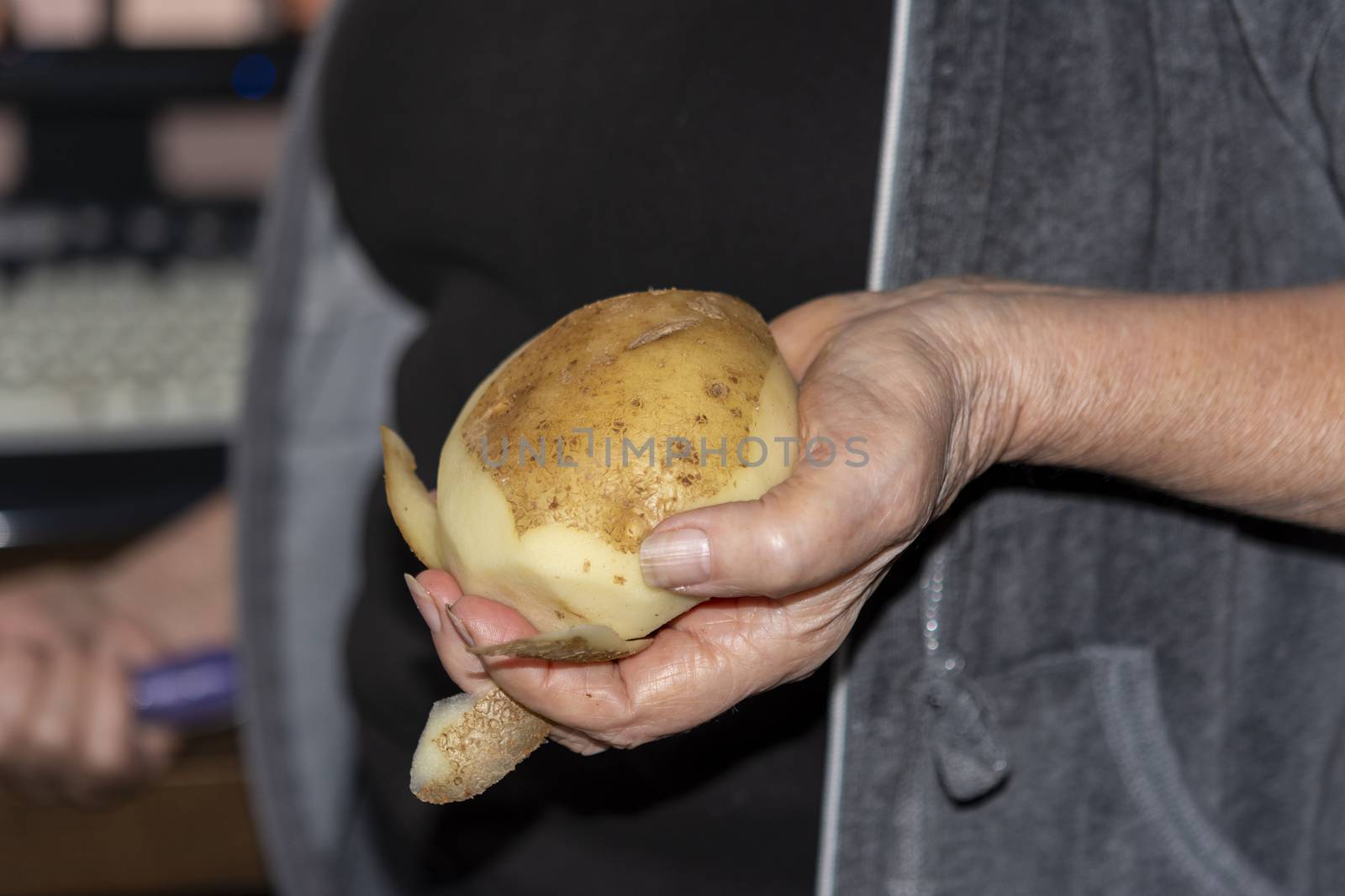  Incompletely peeled potatoes in hand and knife in other hand