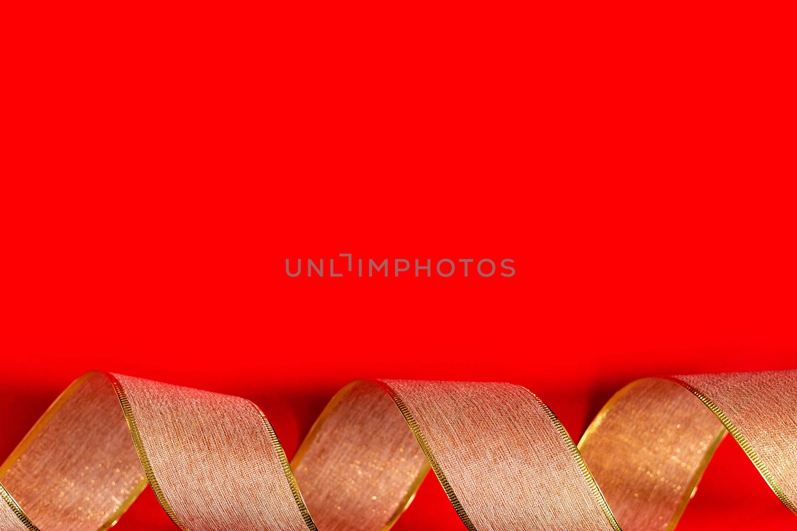 Golden ribbon against red background. gold packaging ribbon curls on red background, new year background, copy space, place for text, banner, holiday concept, Christmas, new year, Valentine's day.