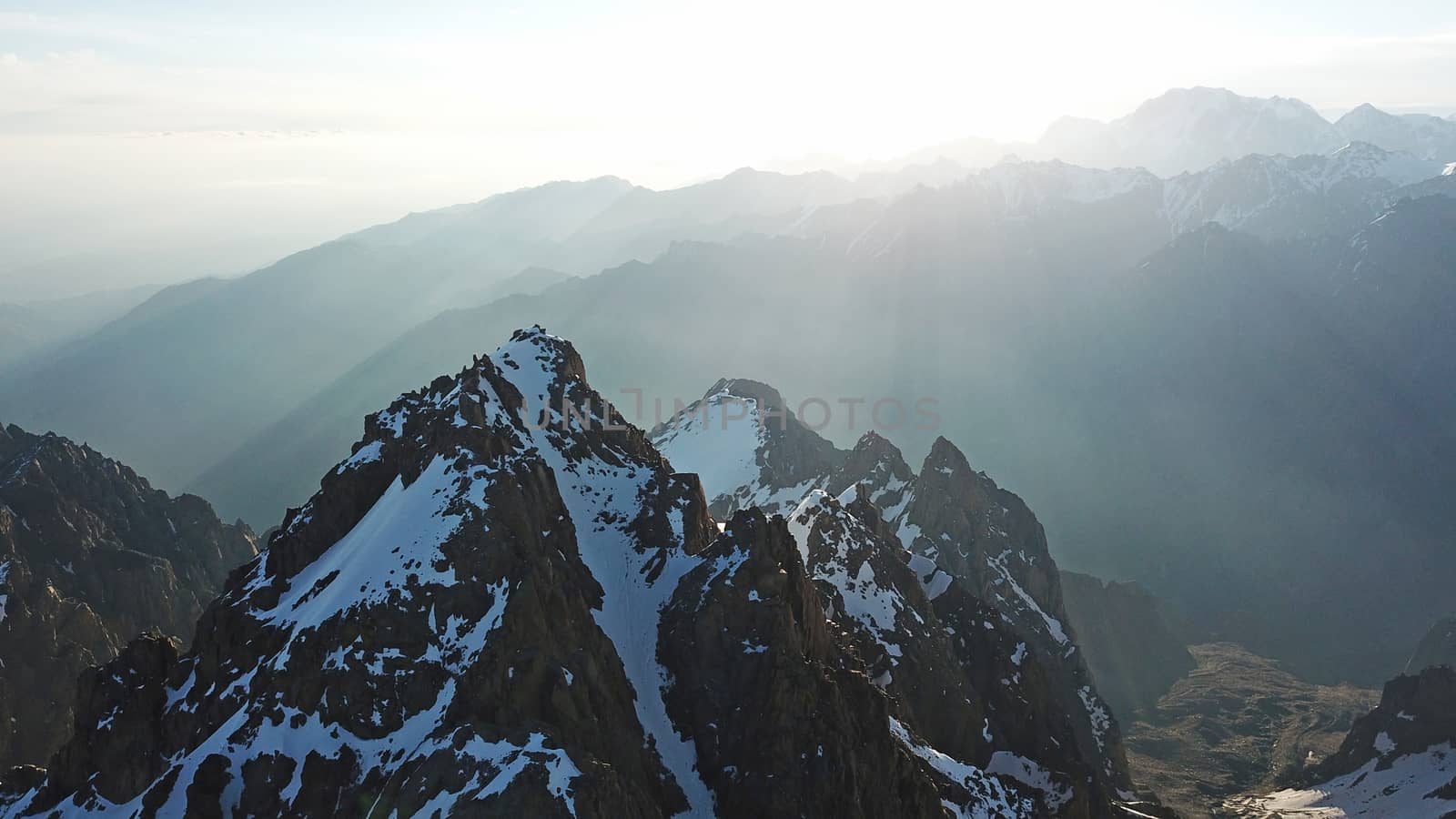 Huge snow mountains. View from the top of the drone. In places, you can see small people climbing to the top. Panorama of steep peaks and rocks, snow cornices. Mountaineering class. Extreme rest.