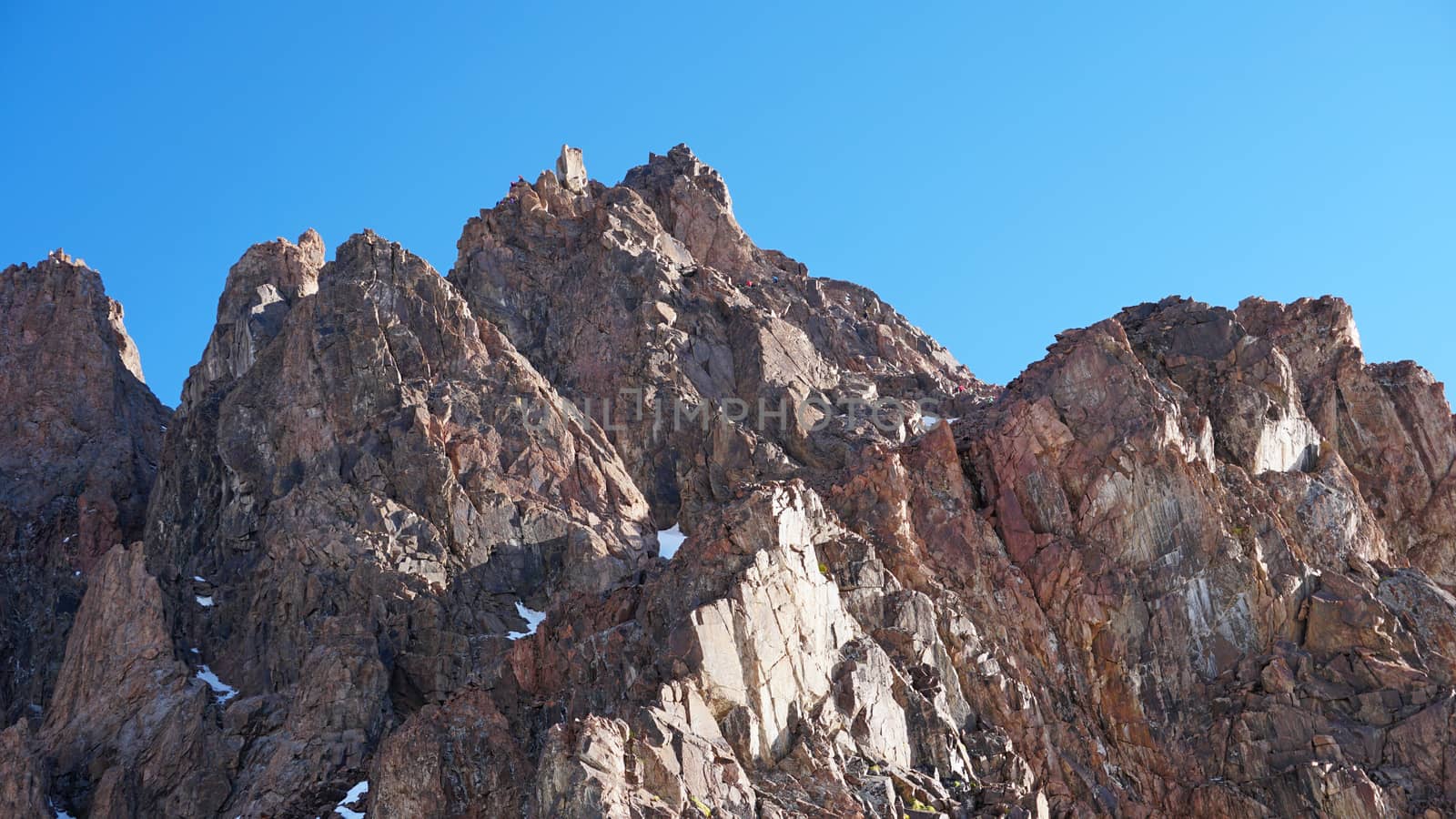 Huge snow mountains. View from the top of the drone. In places, you can see small people climbing to the top. Panorama of steep peaks and rocks, snow cornices. Mountaineering class. Extreme rest.