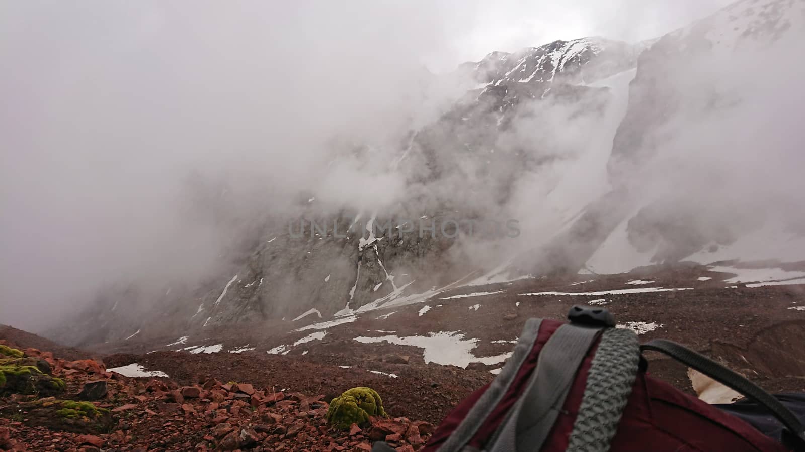 Backpack in the snowy mountains. Fog is coming. by Passcal