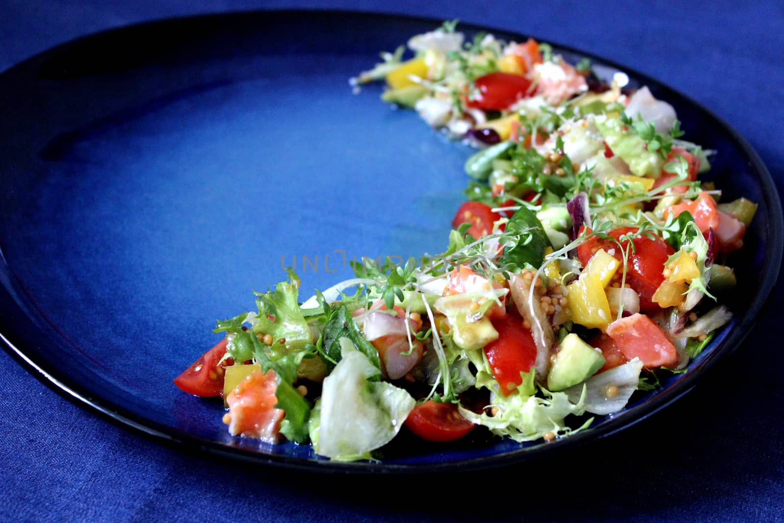 FDiet vegetable salad on a blue plate and a blue background.Texture or background