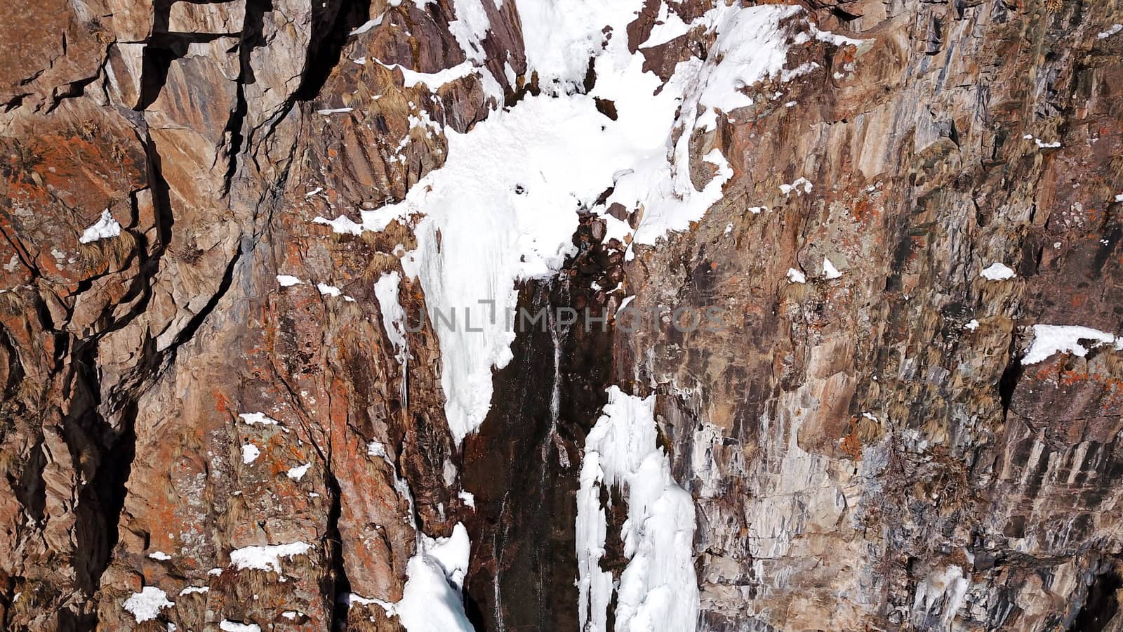 Winter forest high in the mountains. Top view from the throne of the snowy mountains and hills. Fir trees and trees grow on the hills. Some trees are covered with snow. The shadow of the trees.