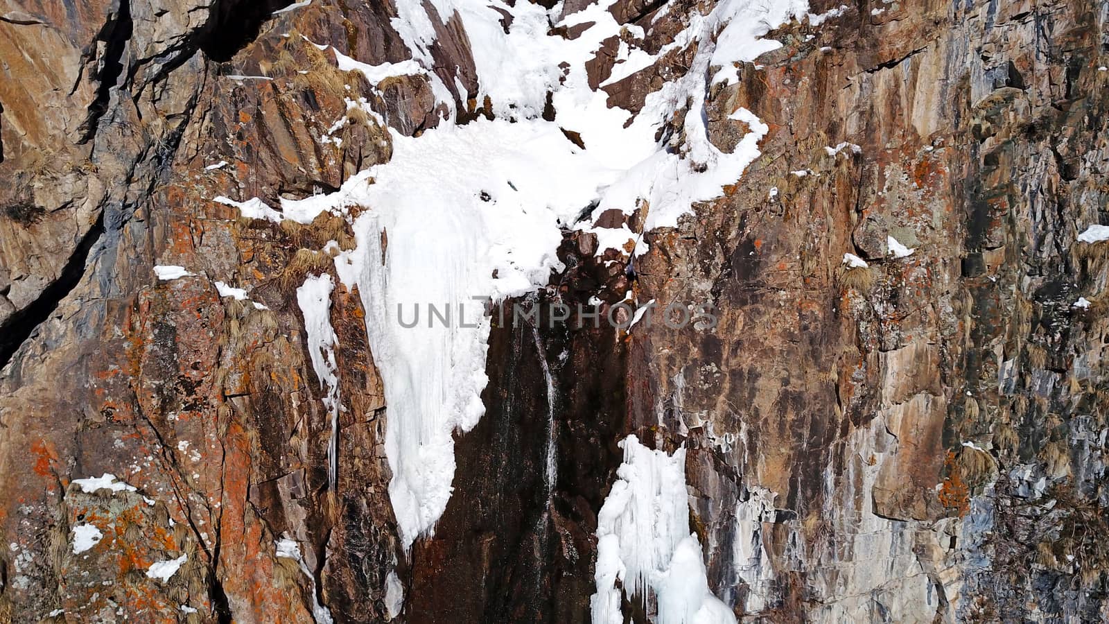 Winter forest high in the mountains. Top view from the throne of the snowy mountains and hills. Fir trees and trees grow on the hills. Some trees are covered with snow. The shadow of the trees.