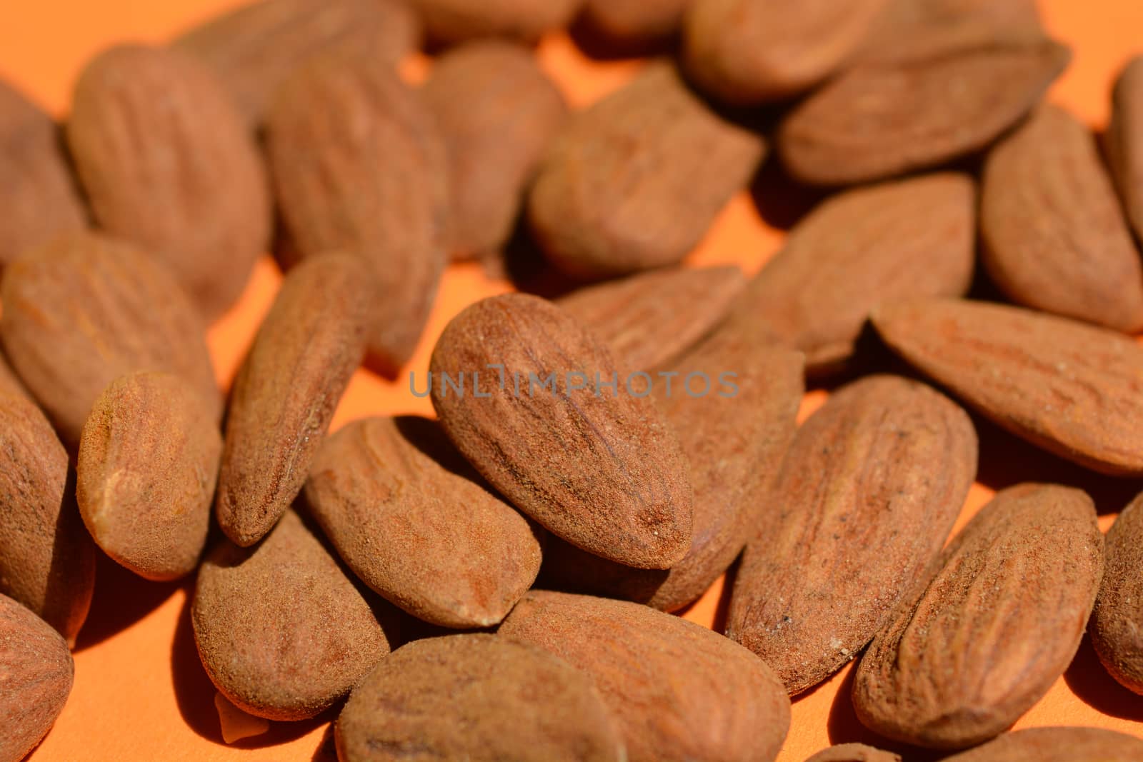 Raw almonds on orange paper background