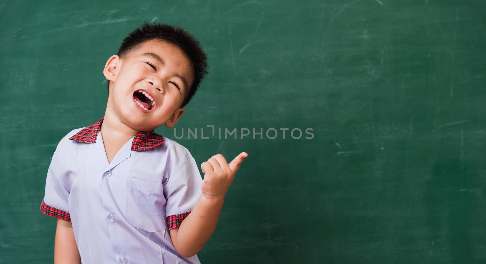 child from kindergarten in student uniform smiling on green scho by Sorapop