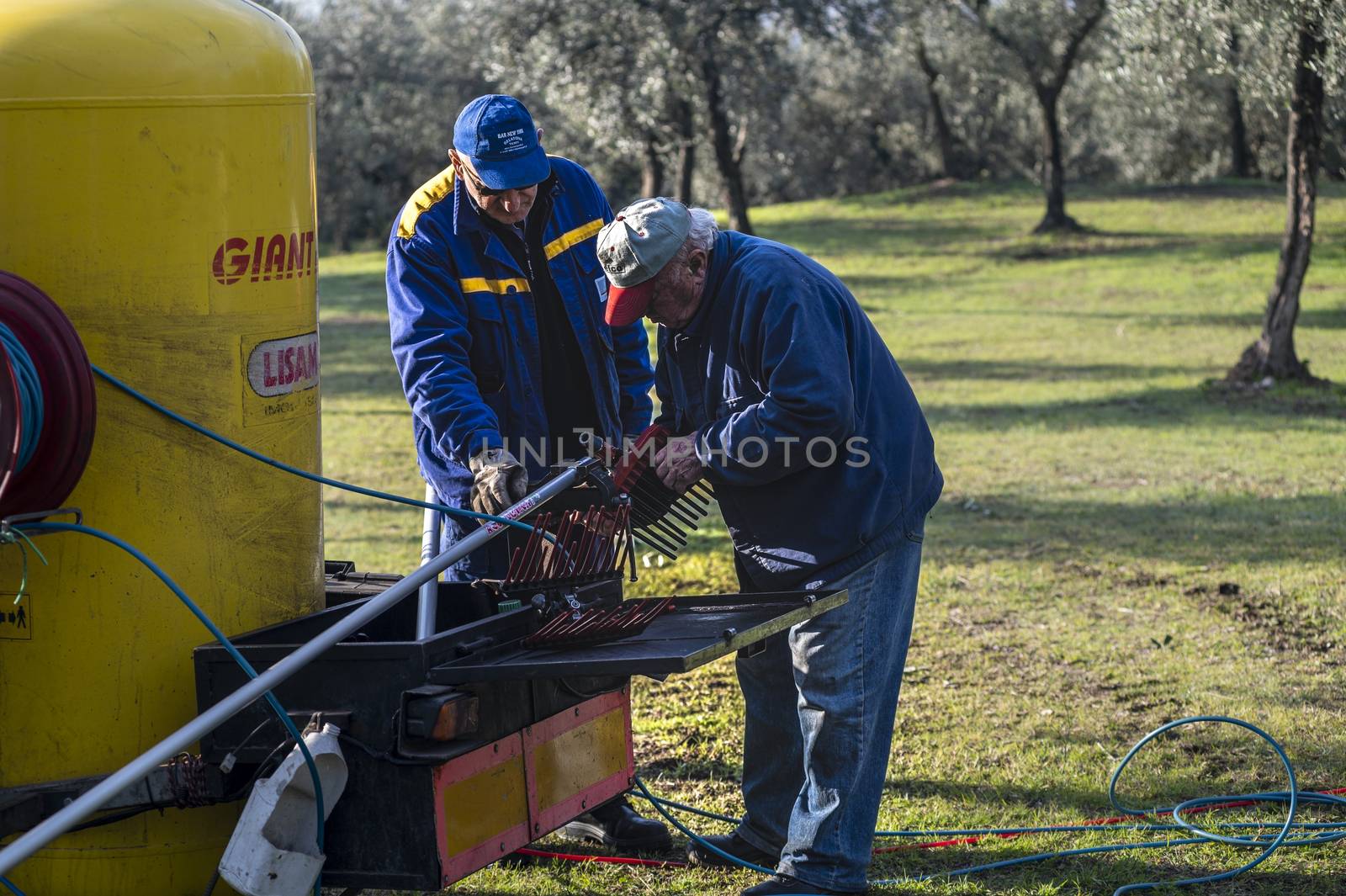 terni,italy november 26 2020:workers dismantling a hydraulic rake for the olive harvest