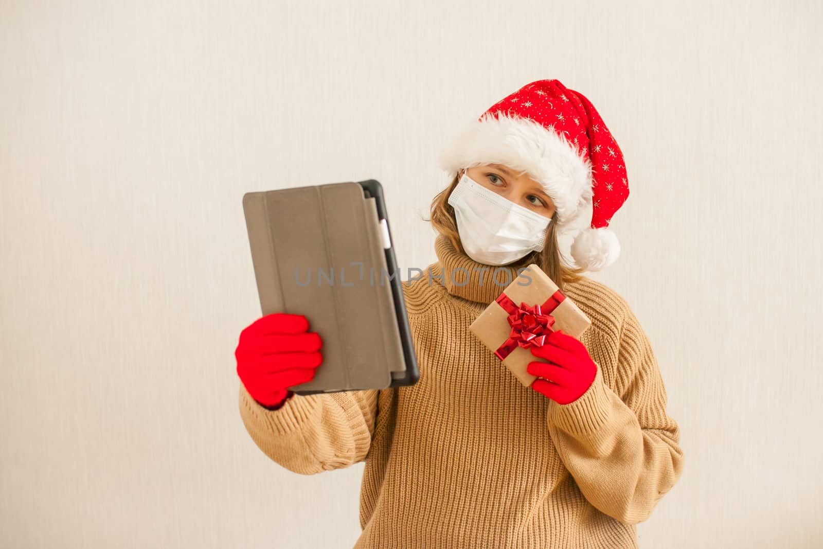 girl in a Santa hat and a medical protective mask congratulates family and friends online. New Year 2021 by malyshkamju