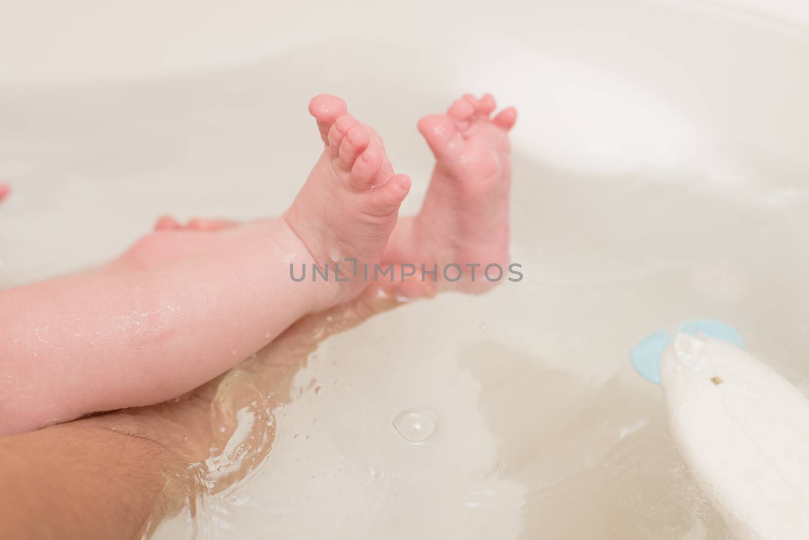 Cute baby having bath in white tub.