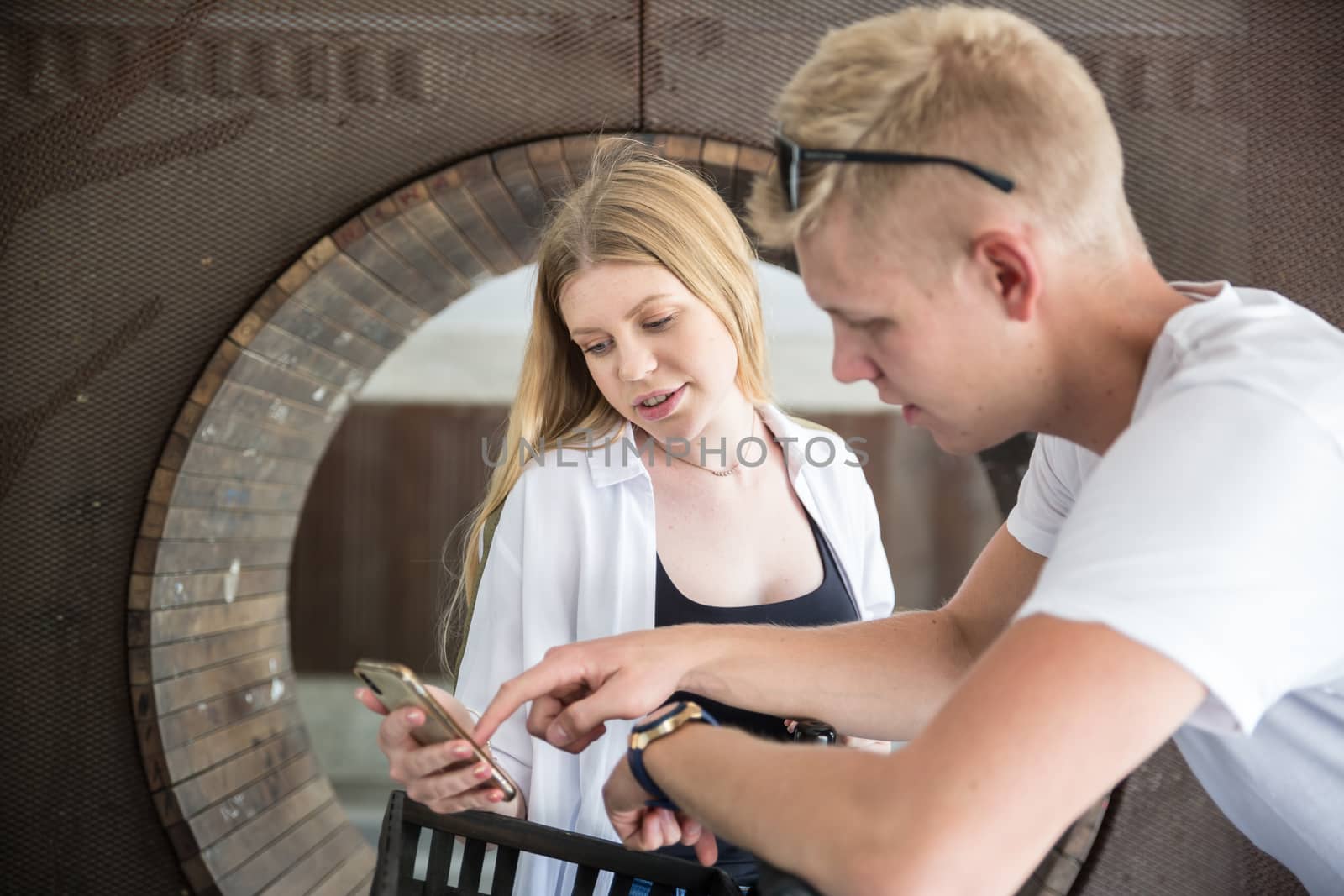 Happy young couple using smart phone application outdoors in urban environment.