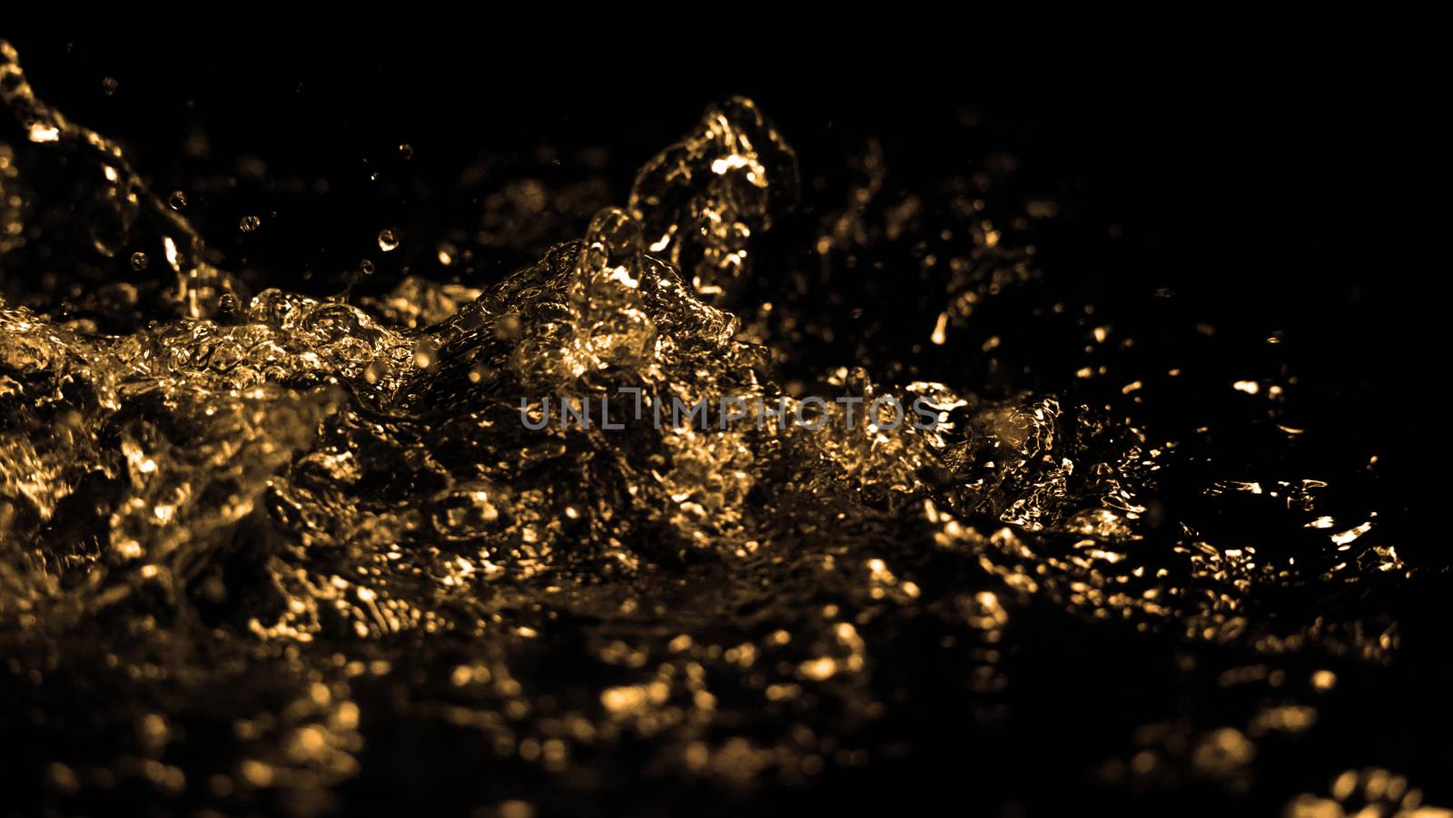 Hi speed close up images of oil liquid from diesel gasoline splashing and moving up to the air on black background for represent power of fuel liquid that active and powerful. studio shot premium gold color tone.