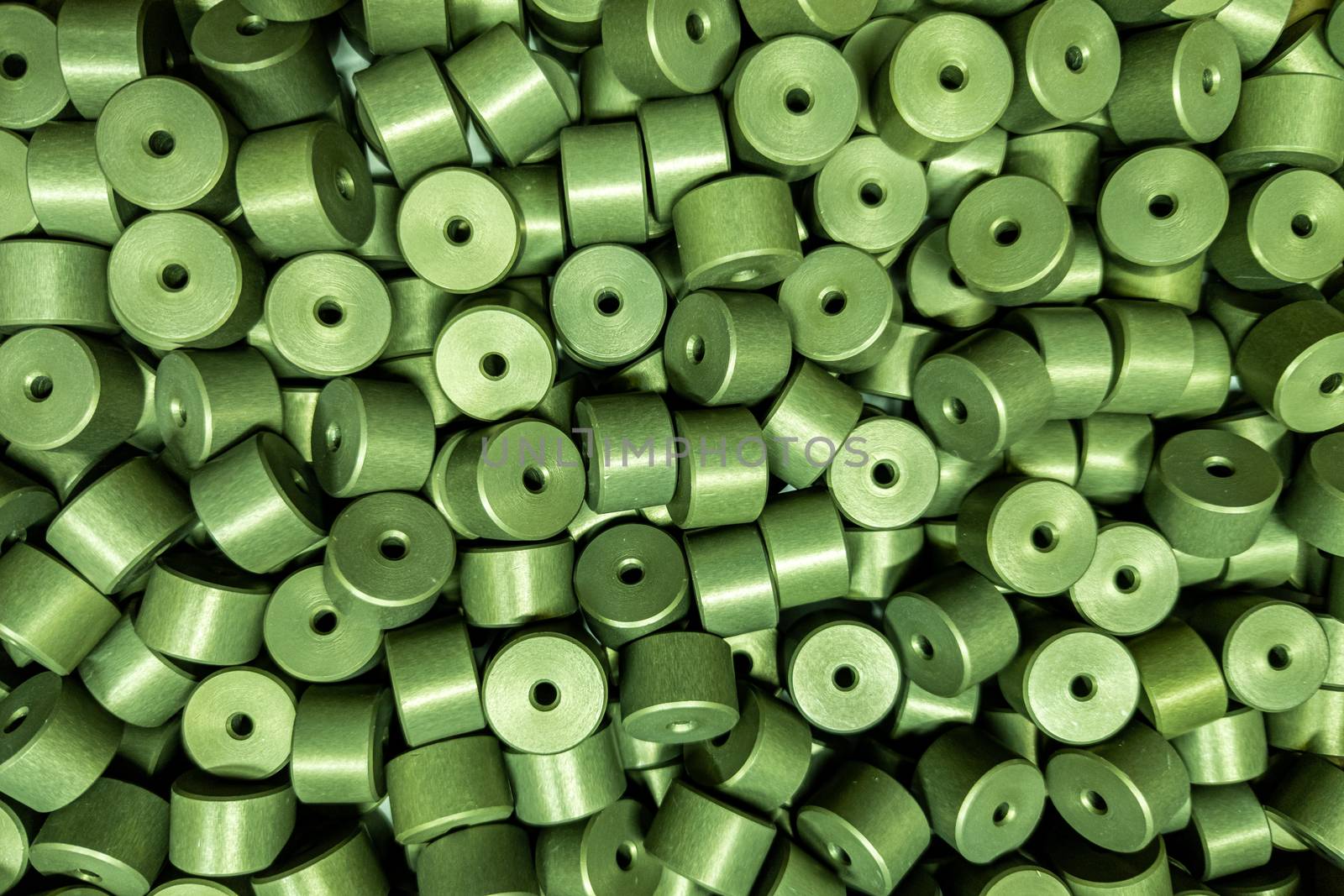 full frame batch of aluminium cylinder parts after anodizing with filling in green chromate solutions, flat industrial background
