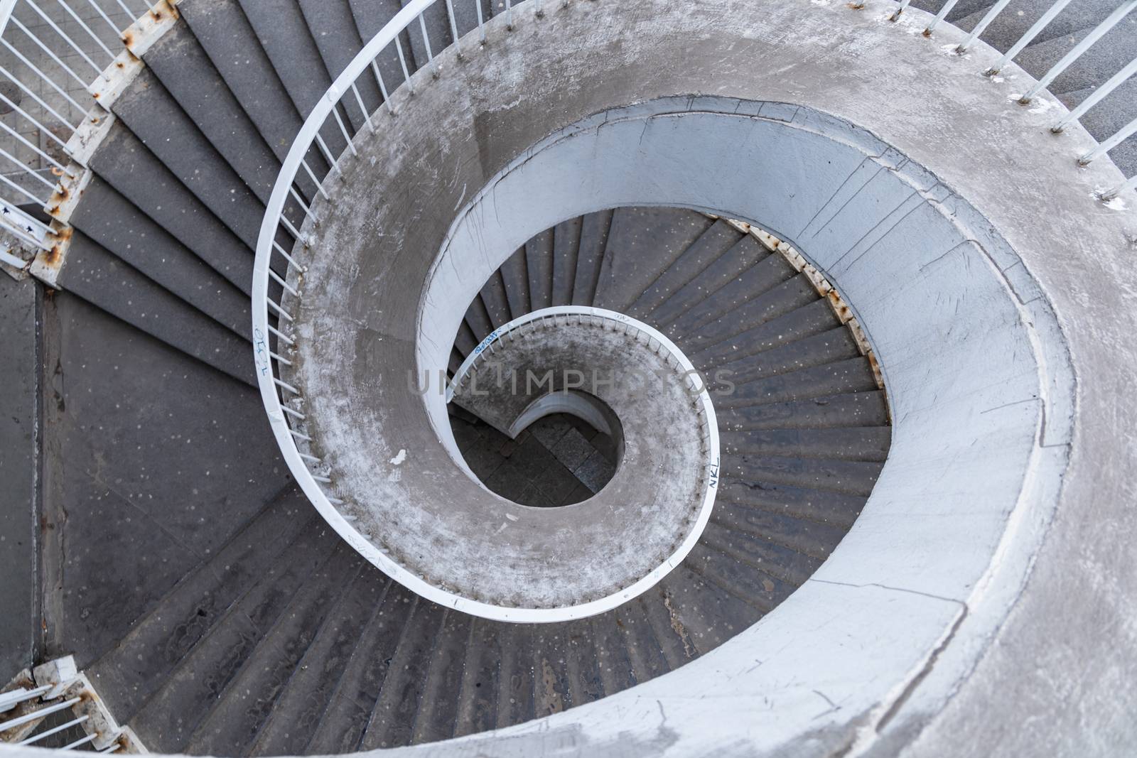 Old outdoor concrete spiral staircase with rusty metal railings by Wierzchu