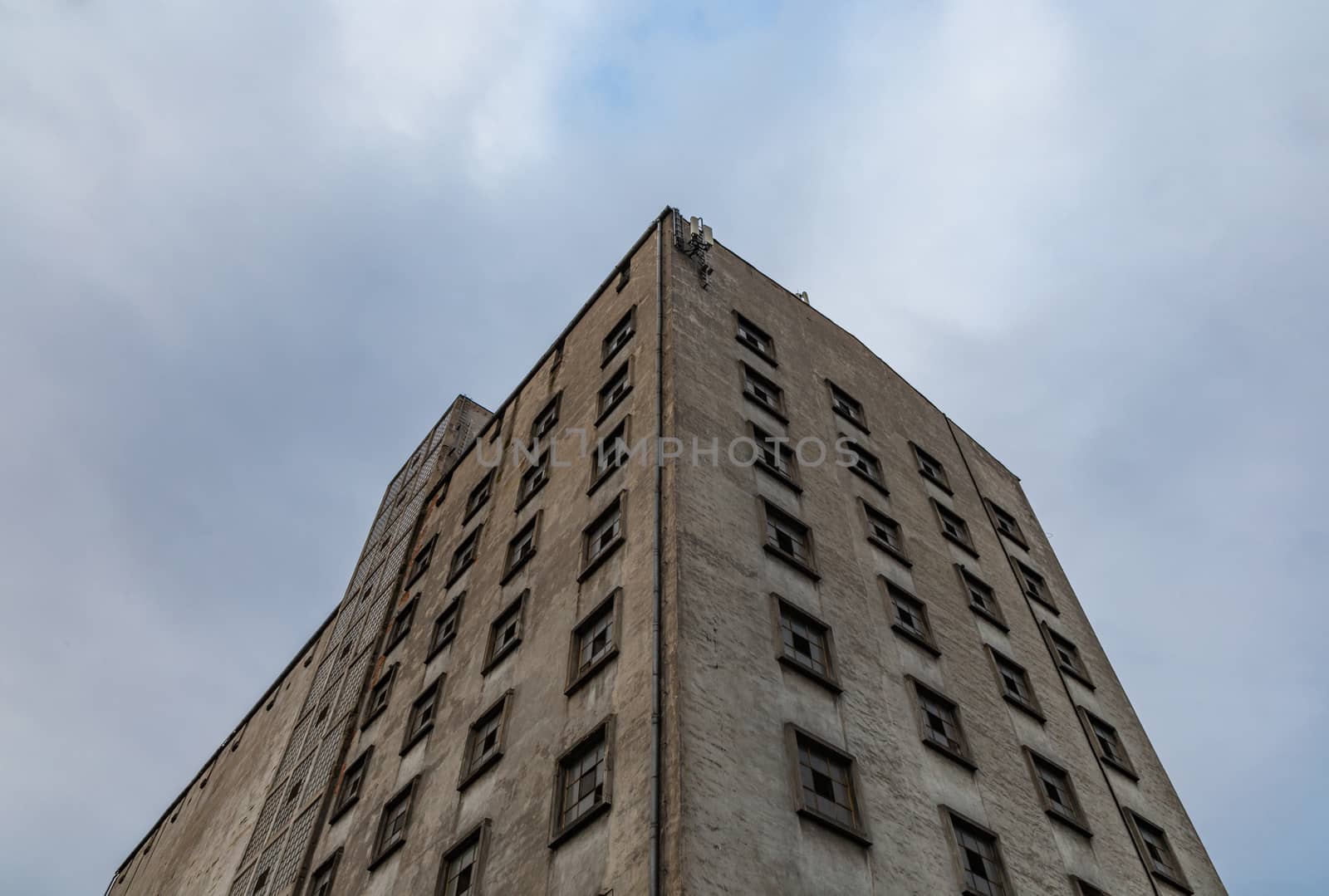 Upward view to old industrial building with holes in windows by Wierzchu