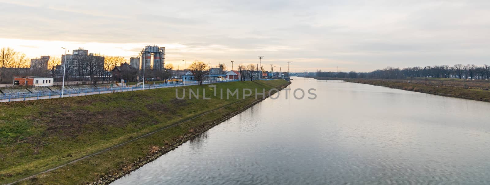 Panorama of Long green coast near Odra river with few trees and buildings