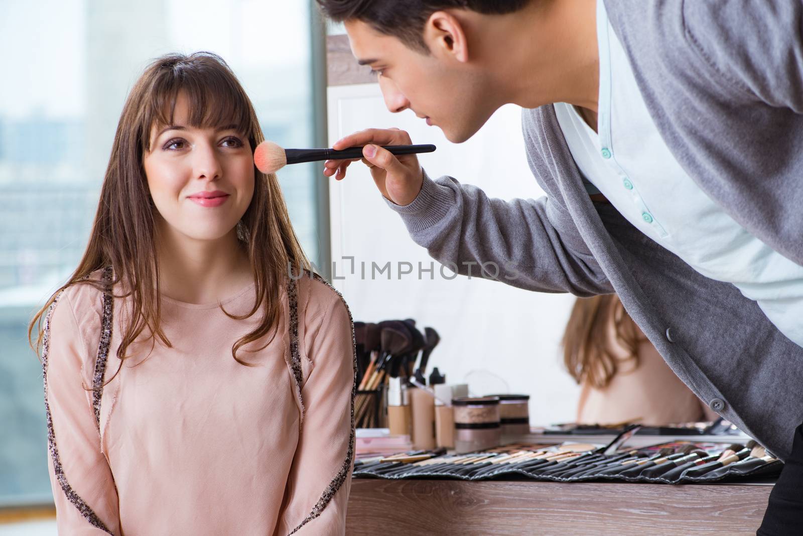 Man doing make-up for cute woman in beauty salon by Elnur