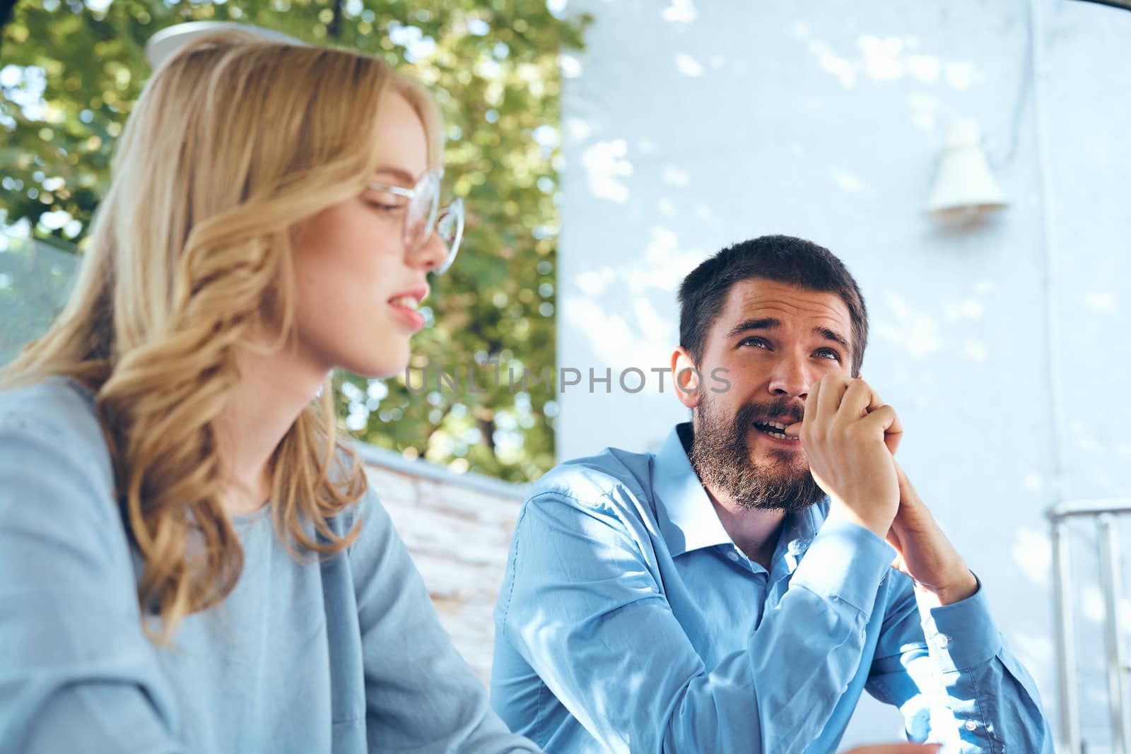 Man and woman communicate in the park outdoors in blue shirts employees friends work by SHOTPRIME