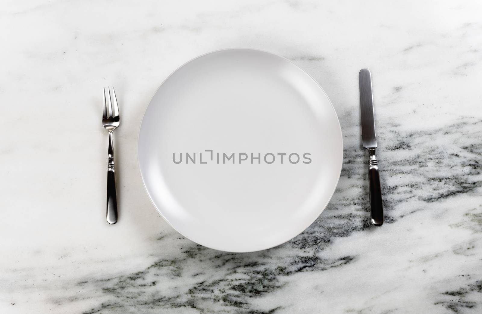 Dinner setting with clean plate, knife and fork on marble table  