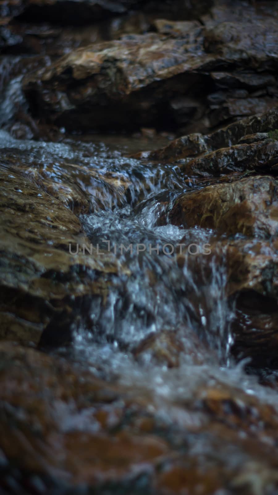 Close up of mountain river flows between picturesque summer stones. Rocks in the mountains with water flowing