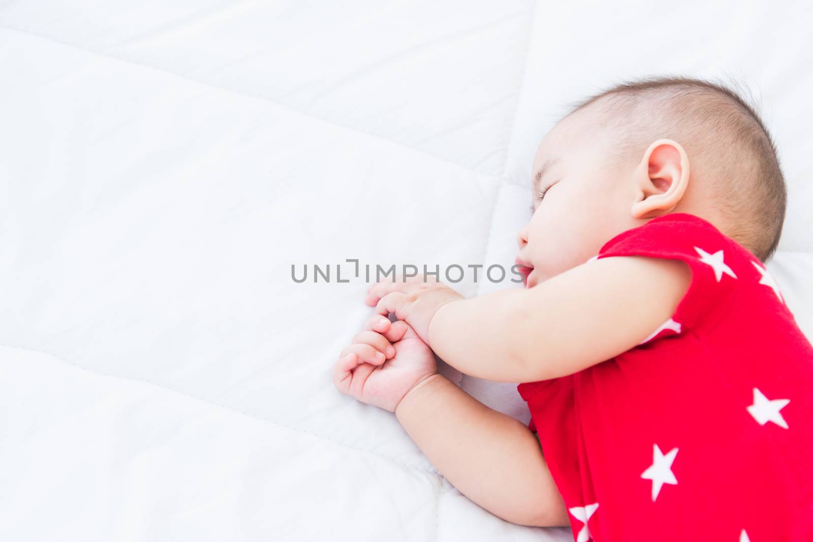 newborn little baby sleeping on white bed at home by Sorapop