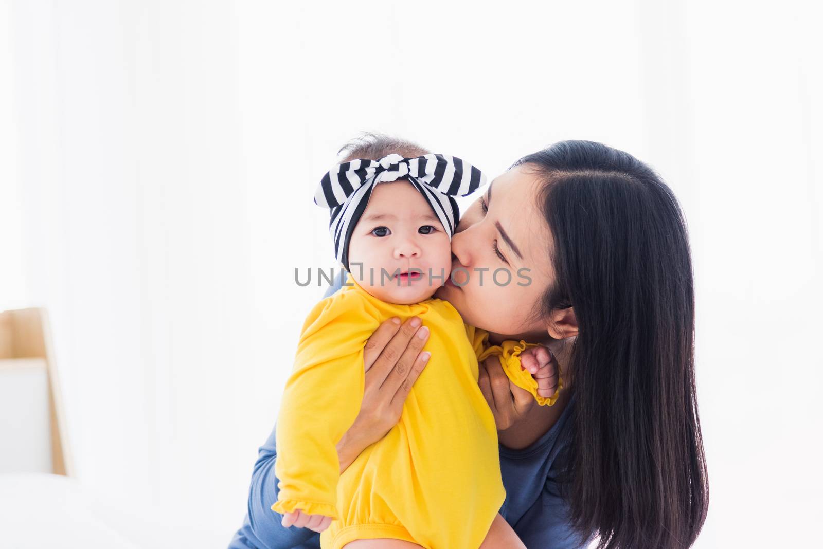 Portrait of beautiful young Asian mother kissing her infant newborn baby in a white bed, The mom loves his child, Healthcare and medical and mother day concept