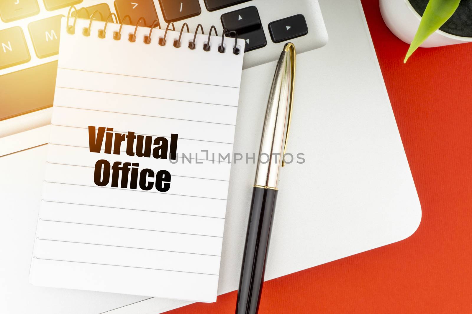 VIRTUAL OFFICE text with notepad, laptop, fountain pen and decorative plant on red background. Business and Copy Space Concept