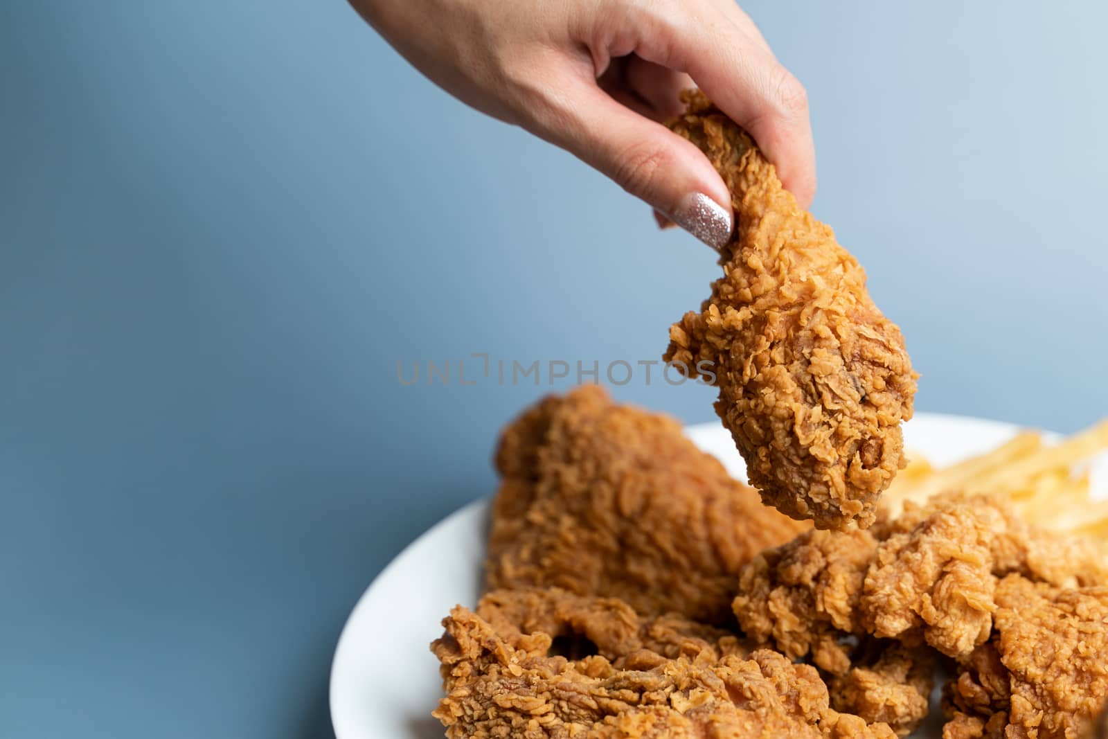 Hand holding drumsticks, crispy fried chicken in white plate on by sirawit99