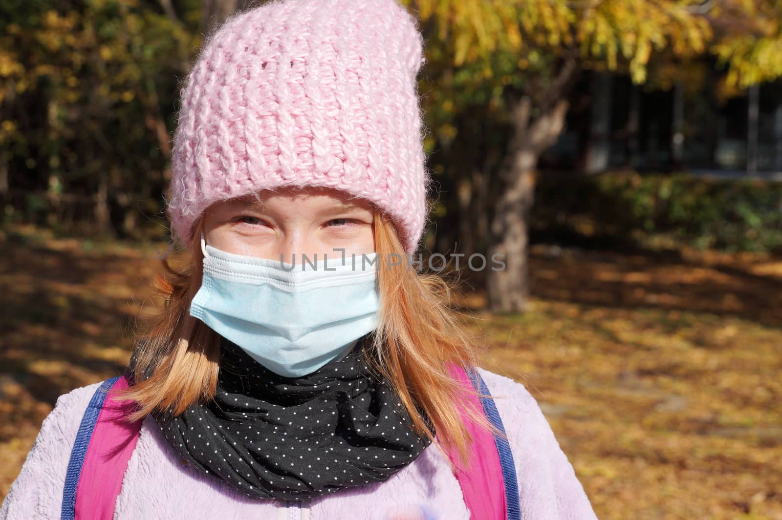 portrait of a teenage girl in a medical mask in an autumn park.