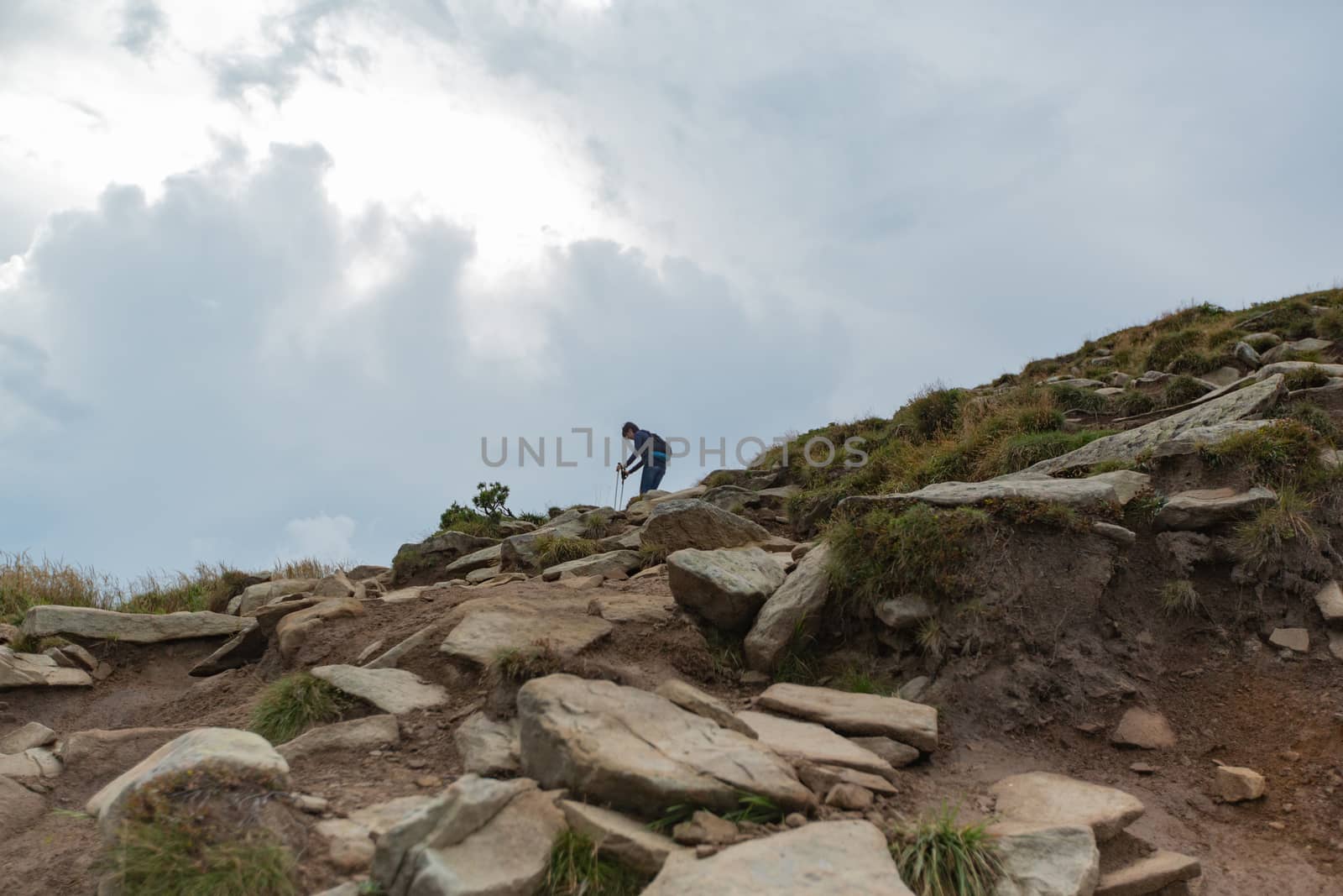 People descend down a large green mountain range. Mountain Hiking by TrEKone
