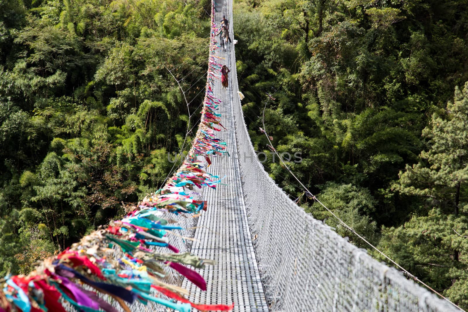 Ghasa, Nepal - November 05, 2014: Local people crossing a suspension bridge on the Annapurna Circuit