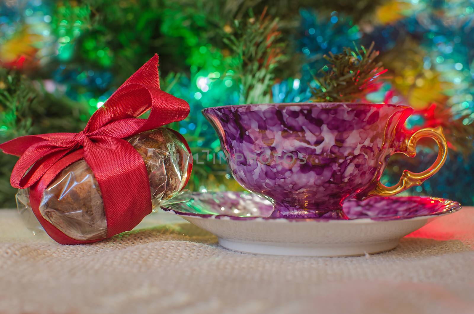 Celebration present and tea mug on blurred light backdrop. Festive decoration on lighted background