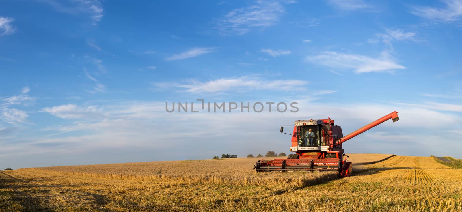 Ramlose, Denmark - August 24, 2016: Panoramic view of a combine harvester at work
