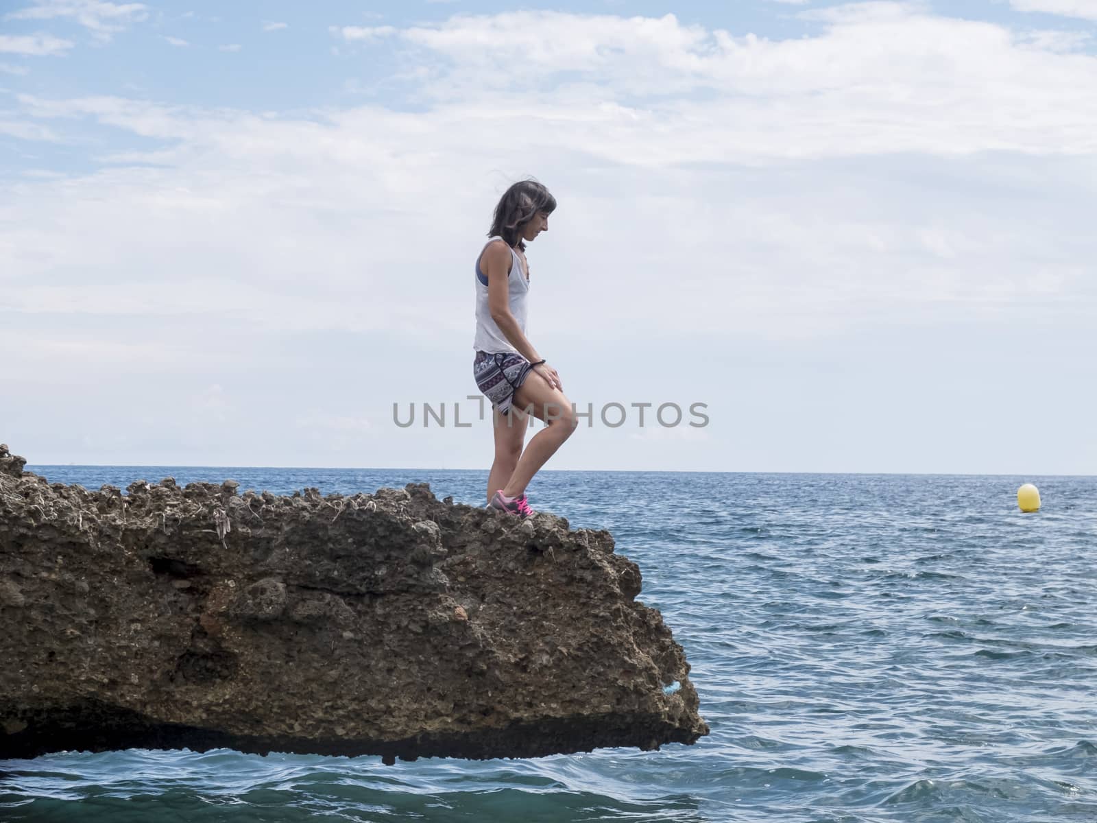 Side view of a woman standing on sea rocks