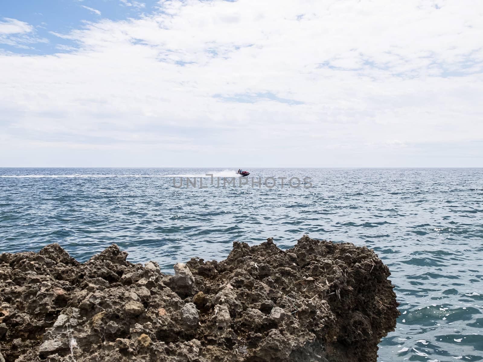 Two Unrecognizable people on a jet ski against horizon